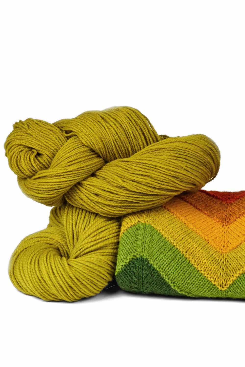 Finkhof Merinowolle dünn gefärbt lindgrün dünne lindgrüne Finkhof Merinowolle aus bio Wolle (kbT) mit Strickpulli darunter, weißer Untergrund