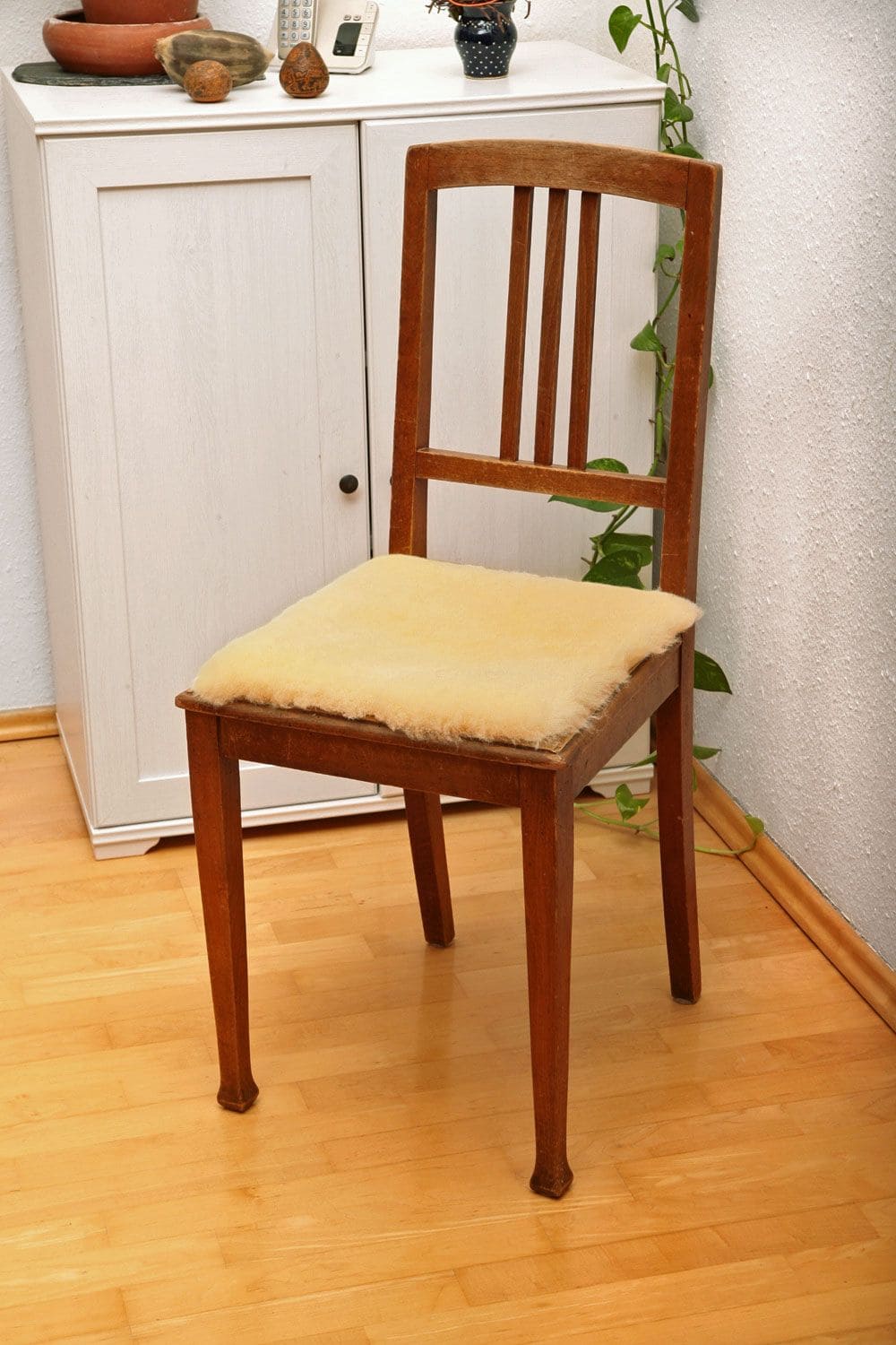 quadratische Stuhlauflage aus relugan gegerbtem Schaffell vom Finkhof liegt auf einem braunen Stuhl