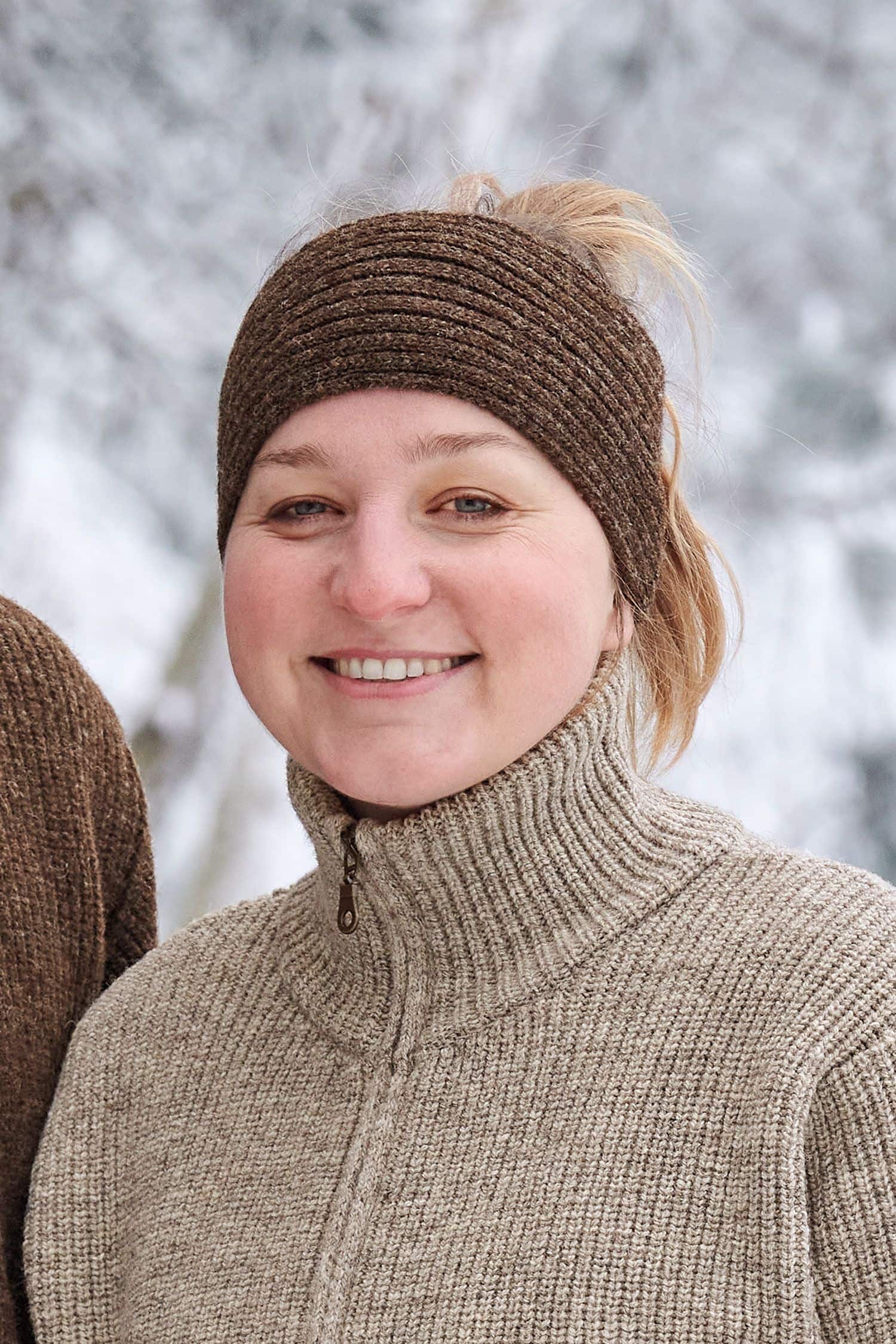 Frau trägt braunes Finkhof Stirnband aus bio Wolle (kbT) und einen Finkhof Troyer