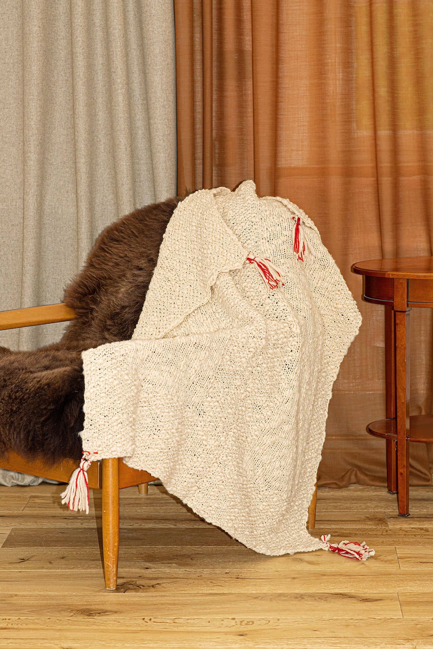 Decke aus Flammengarn liegt auf einem Sessel mit braunem Fell