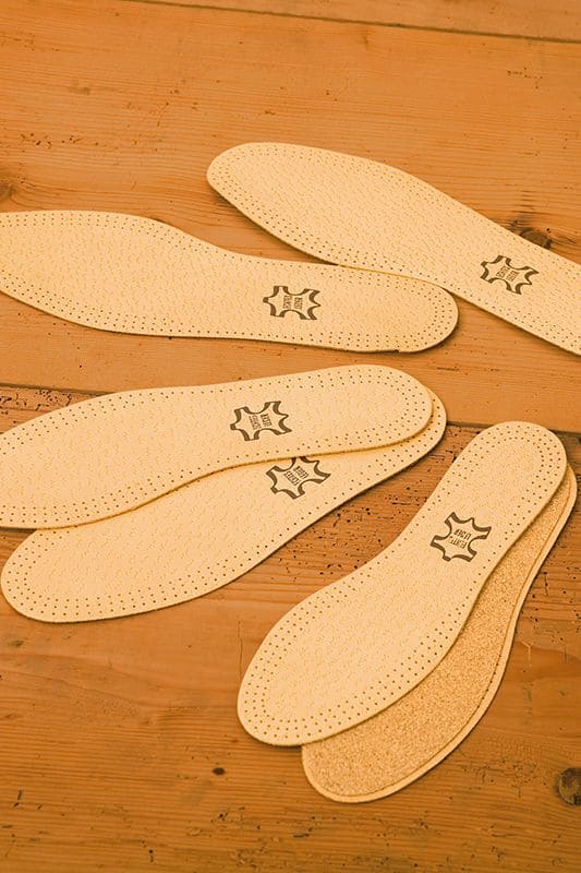 Ledersohlen hellbraune Ledersohlen aus pflanzlich gegerbtem Schafsleder und Kork vom Finkhof in verschiedenen Größen auf Holzboden