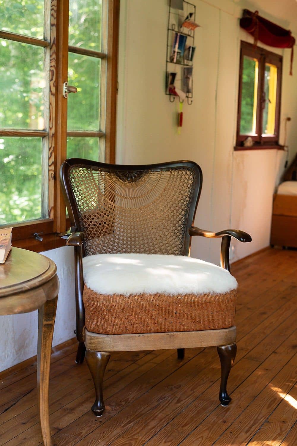 Finkhof Fellauflage pflanzlich gegerbt in weiß ohne Bezug auf Korbstuhl in gemütlichem Ambiente