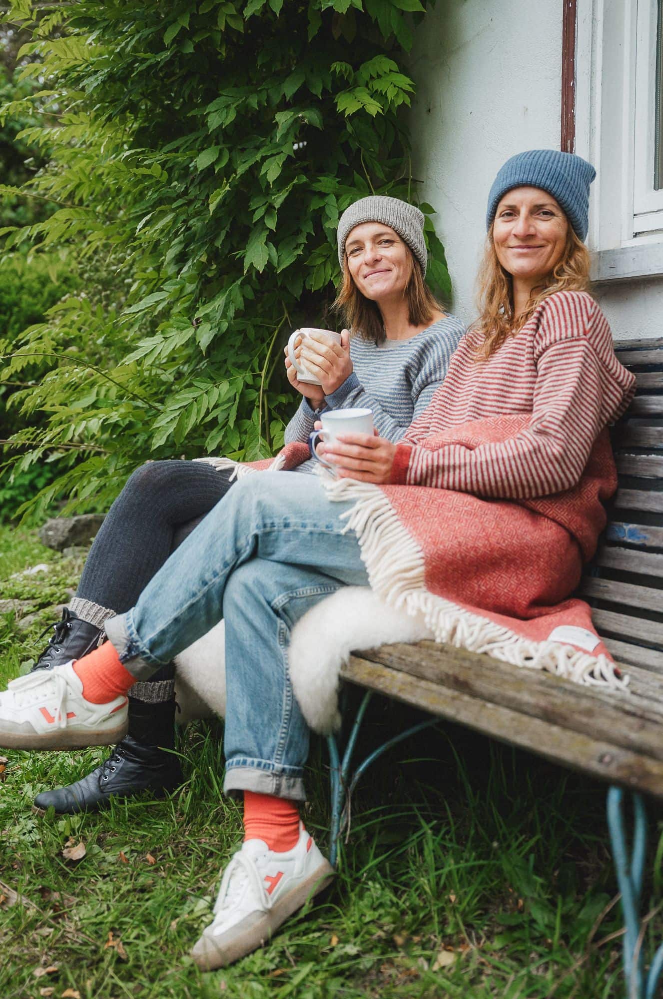 Finkhof-Damen-Ringelpulli Frau mit Ringelpullis aus bio Wolle (kbT) vom Finkhof sitzen mit Mützen und Teetassen auf einer Bank