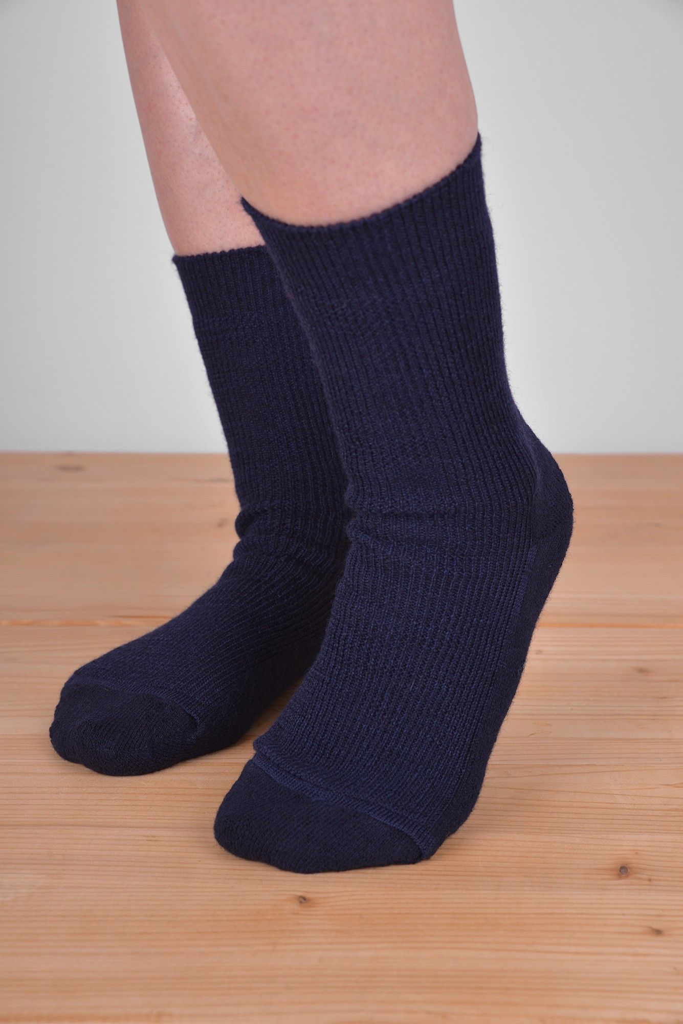 marineblaue dünne Wollsocken aus bio Wolle (kbT) und bio Baumwolle (kbA) vom Finkhof an Model auf Holzboden