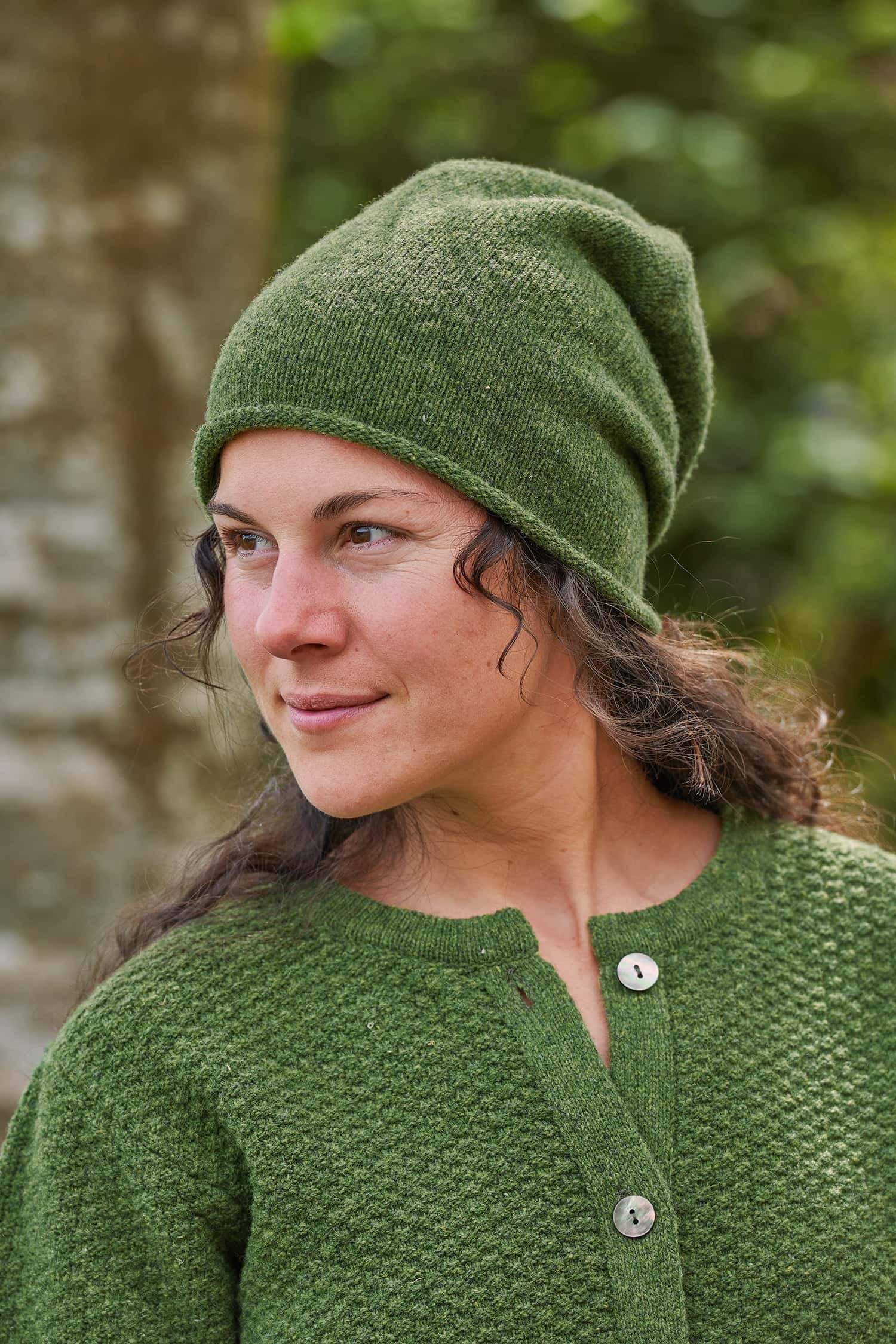 Frau trägt eine grüne Strickmütze mit Rollrand aus Bio-Wolle vom Finkhof mit passender Strukturjacke