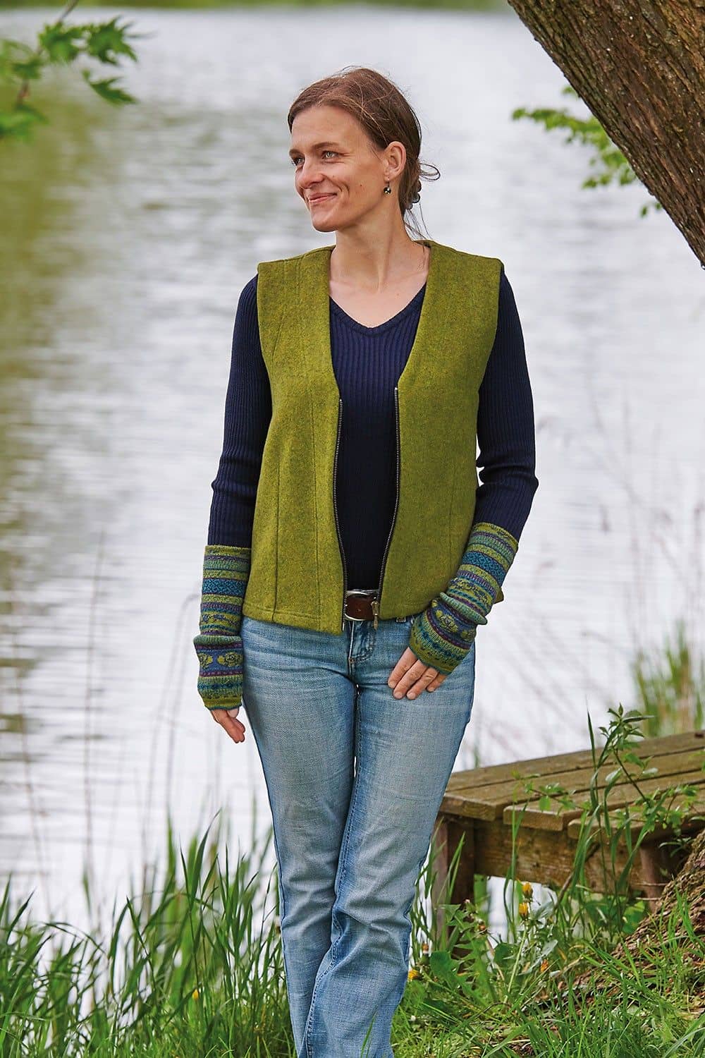 Frau trägt blaues Rippshirt, grüne Weste und grün gemusterte Armstulpen aus bio Wolle (kbT)