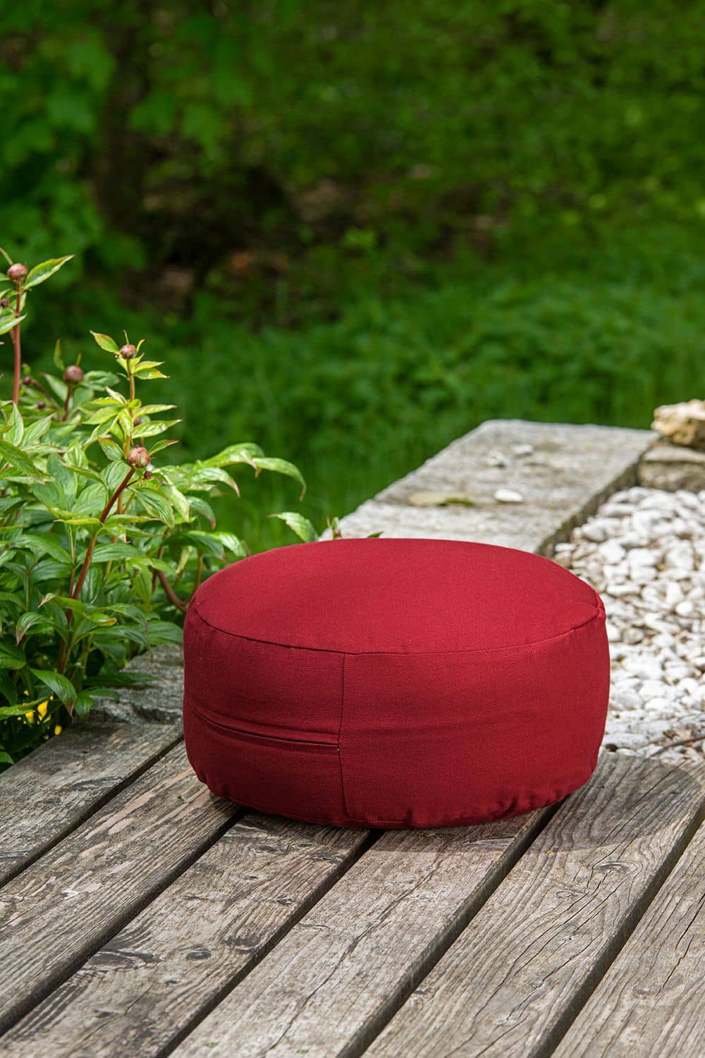 kleines rundes Sitzkissen in rot aus Naturkautschuk, bio Wolle (kbT) und bio Baumwolle (kbA) vom Finkhof auf einer Terasse