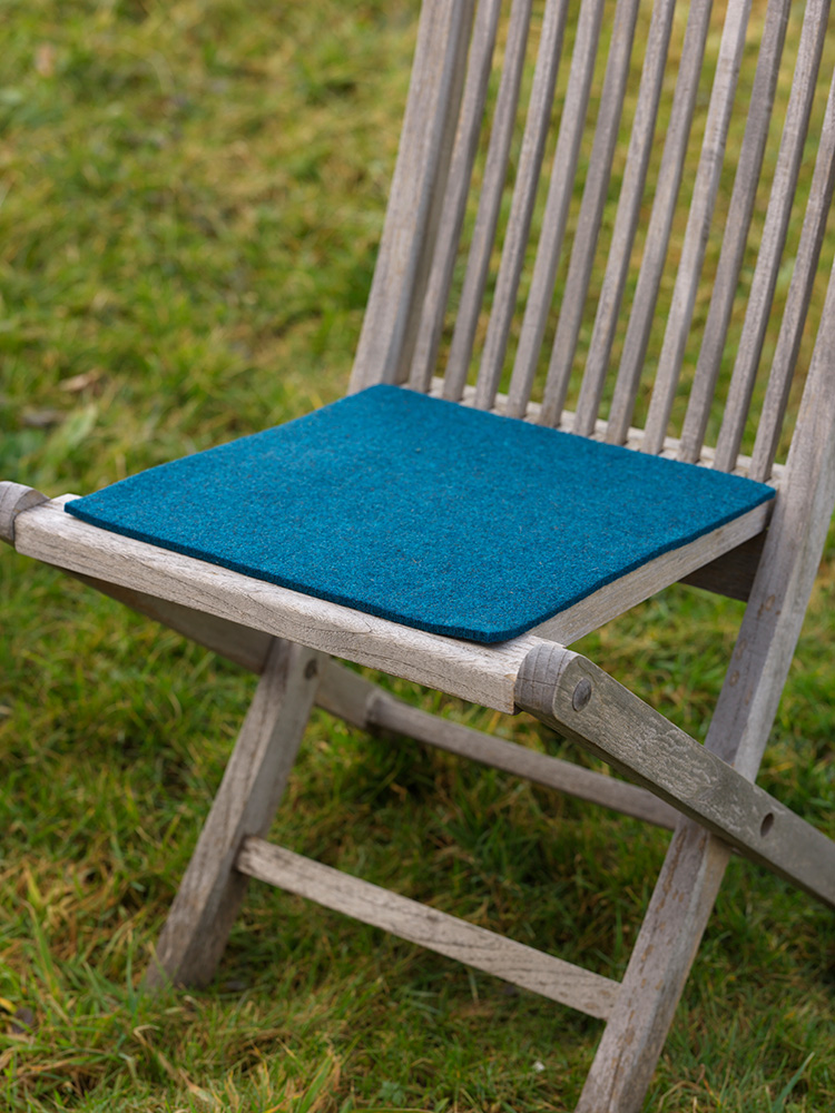 blaue eckige Finkhof Sitzauflage aus bio Wolle (kbT) auf einem Gartenstuhl