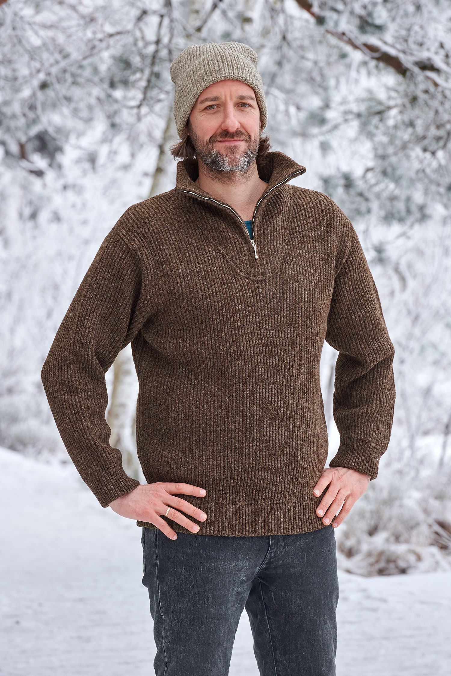 Mann in Schneelandschaft trägt einen braunen Finkhof Troyer aus bio Wolle (kbT) und eine graue Mütze