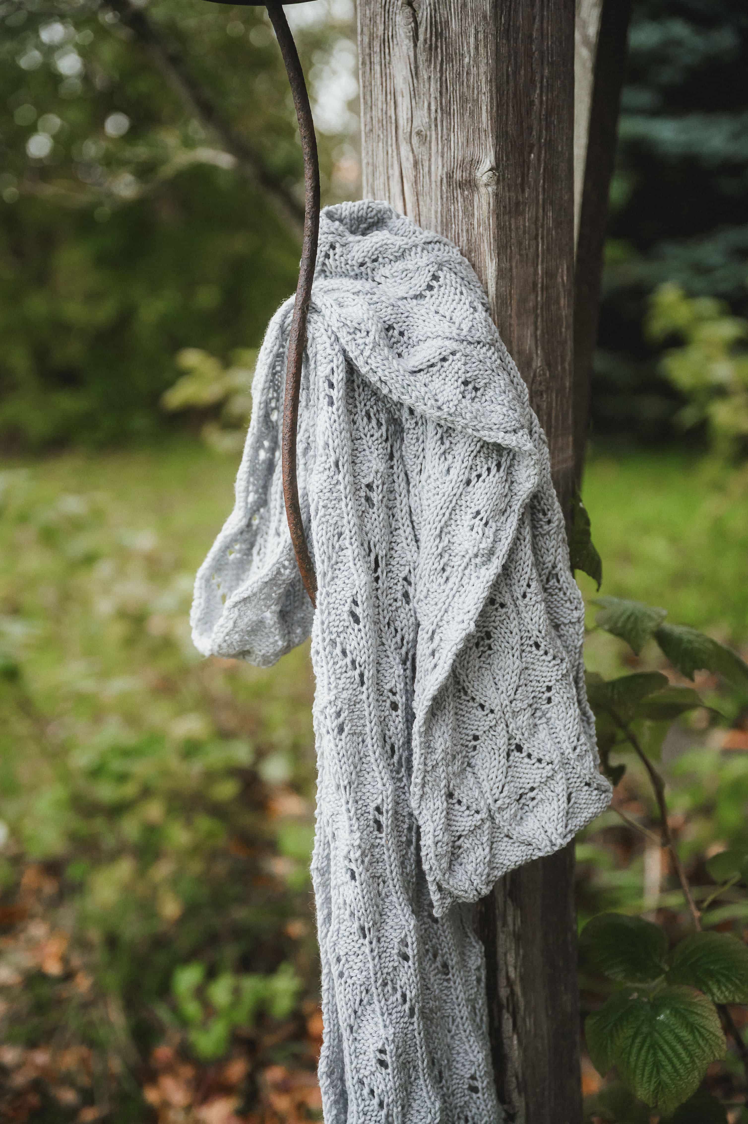 graues Tuch mit Ajourmuster hängt an einem Balken