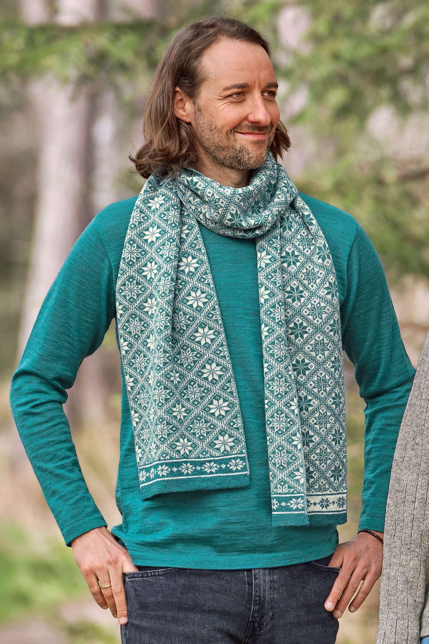 Mann trägt türkises Shirt und Wollschal mit winterlichem Muster aus bio Wolle (kbT)