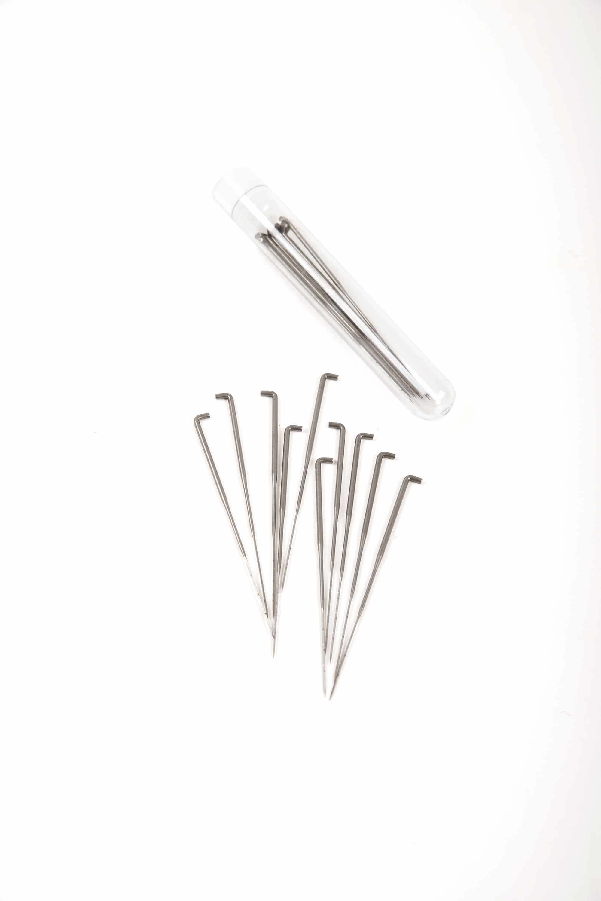 Filznadeln aus Metall ausgebreitet und in Verpackung auf weißem Untergrund