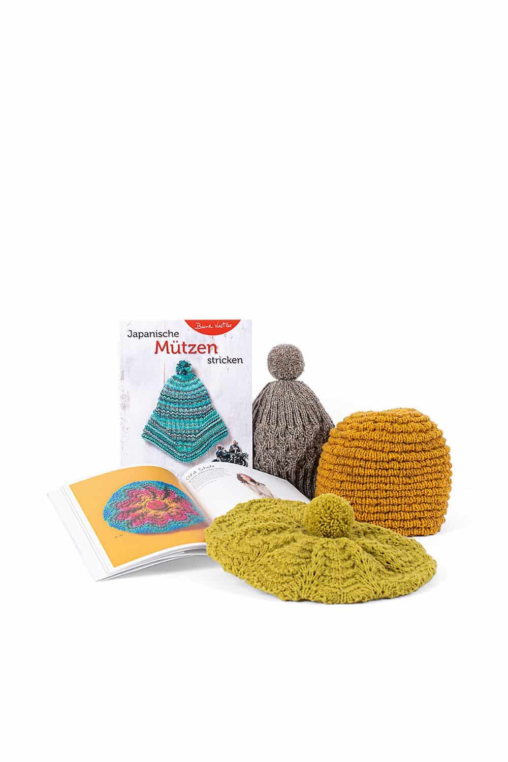 Japanische Mützen stricken Buch ,,Japanische Mützen stricken" mit aufgeschlagenem Exemplar davor und fertigen Mützen