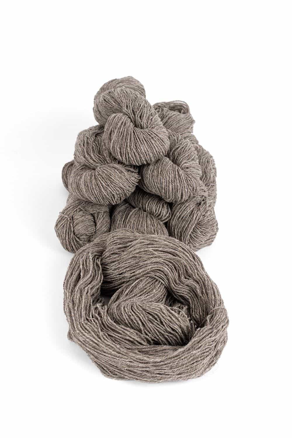 dünne ungefärbte Merinowolle vom Finkhof aus bio Wolle (kbT) in dunkelgrau zur Pyramide aufgestapelt