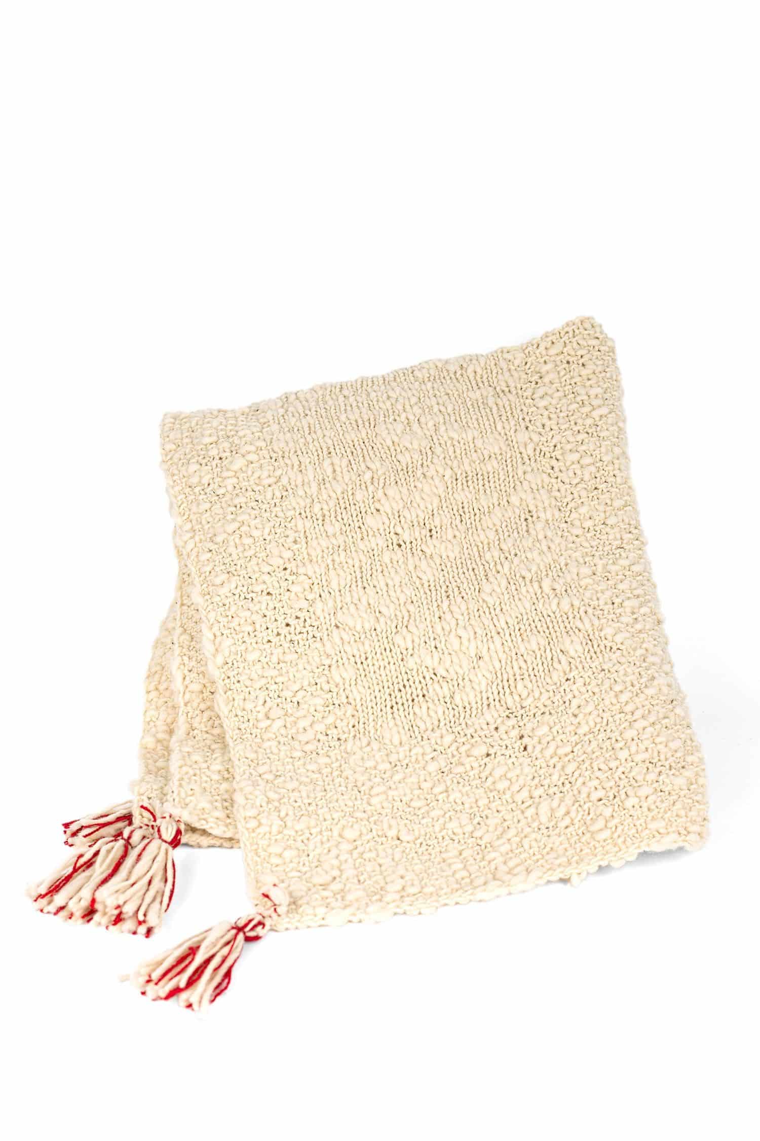 naturweiße Decke mit roten Details aus Flammengarn vom Finkhof aus bio Wolle (kbT) zusammengelegt, Freisteller