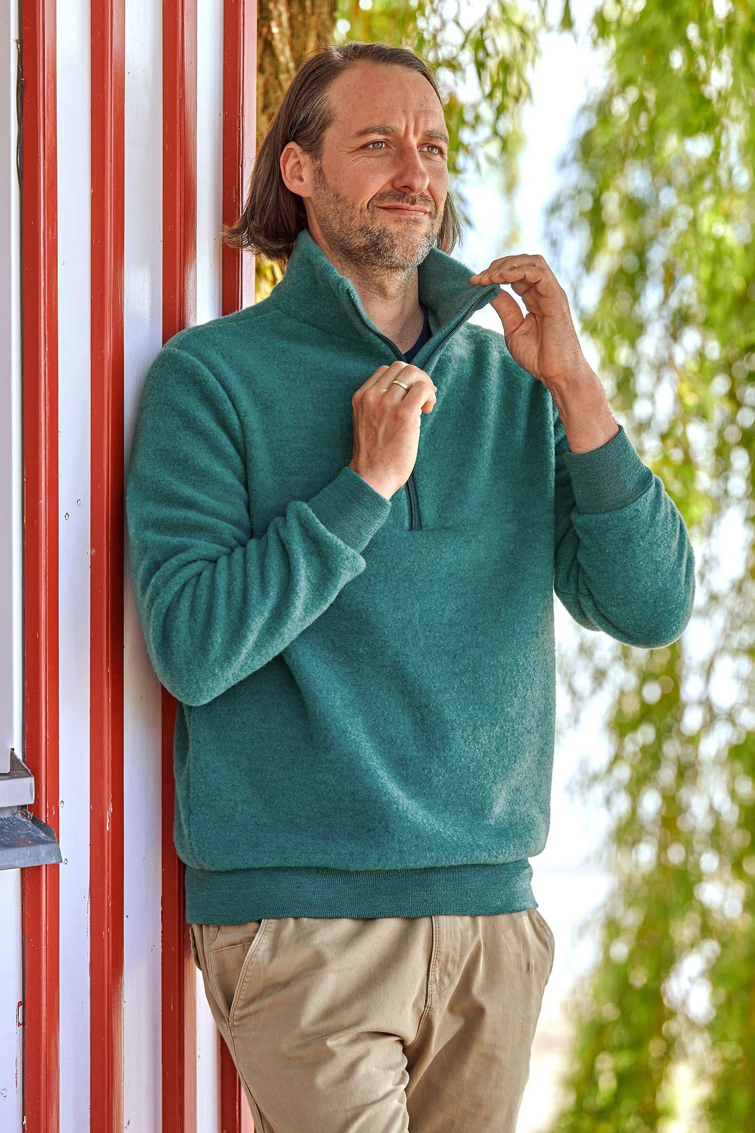 Mann trägt türkisen Wollfleece Pullover mit Reißverschluss aus bio Wolle (kbT) vom Finkhof