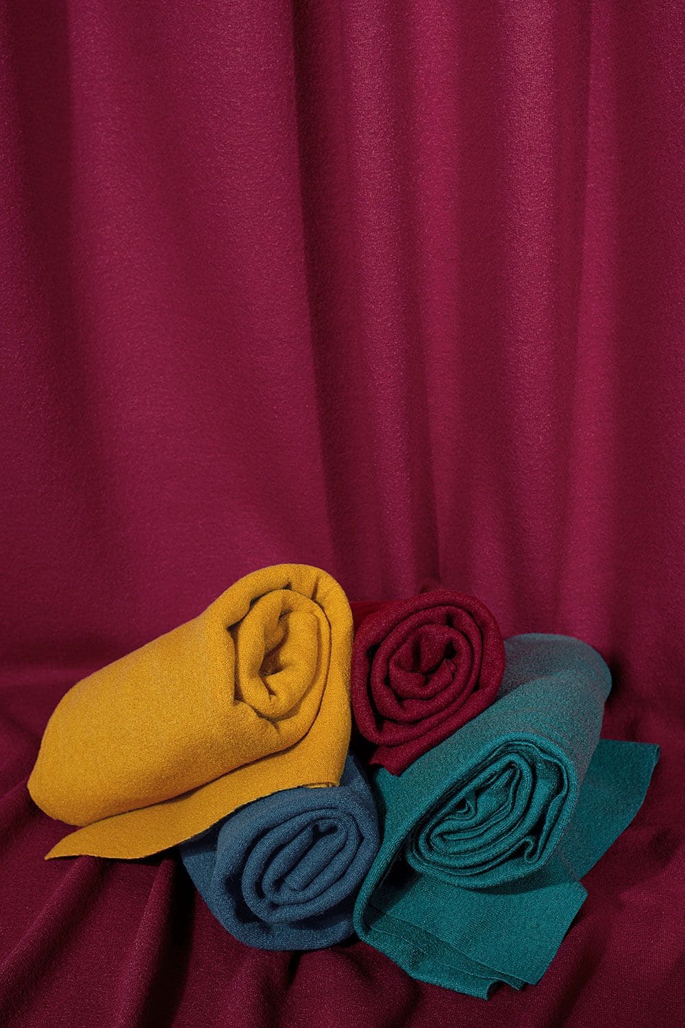 Feinstrick Feintrick Stoffbahnen eingerollt drapiert vor Weinrot mit Schurwolle aus kontrolliert biologischer Tierhaltung