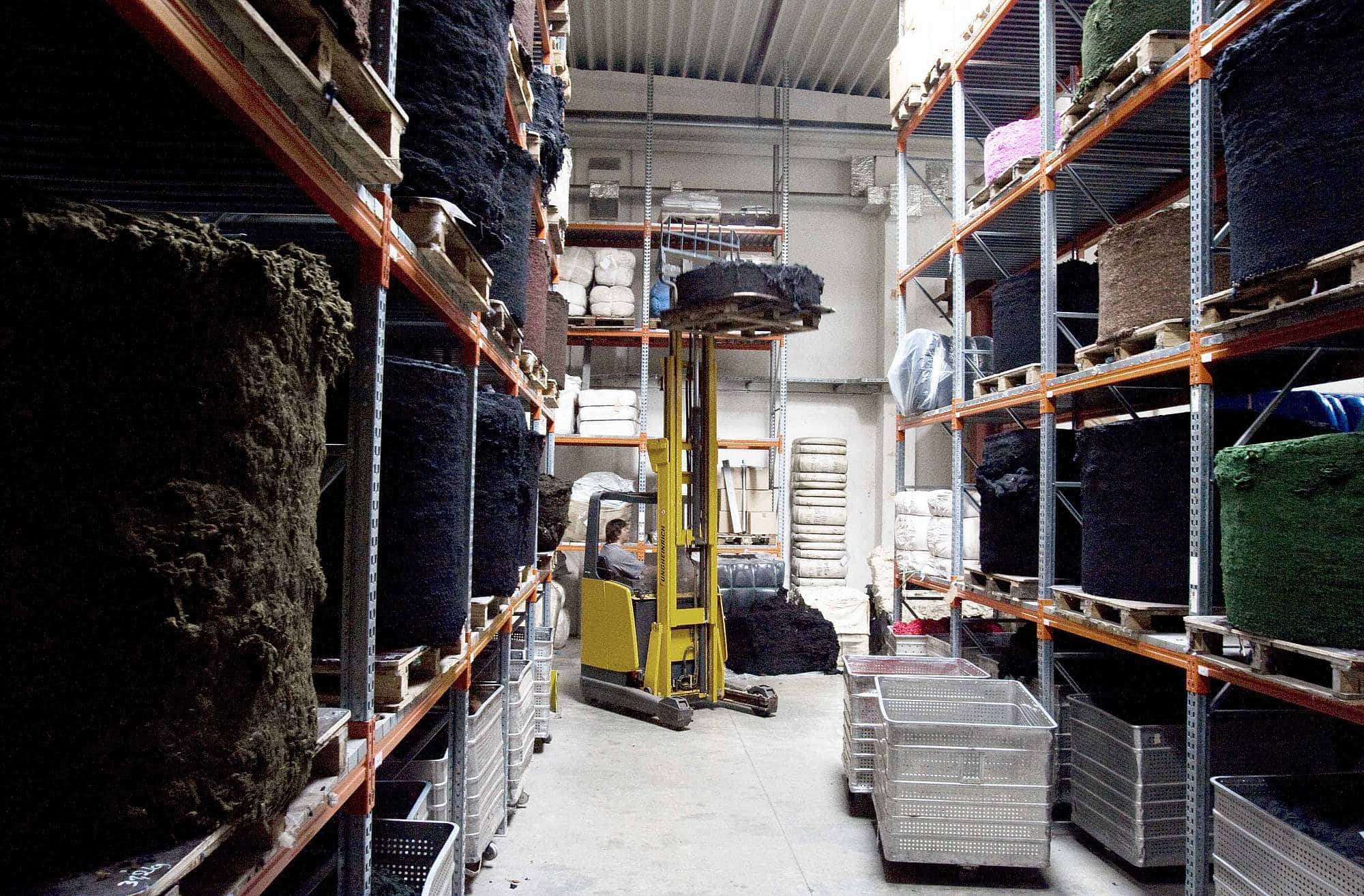 ueber-uns-unsere-wolle-spinnerei-web-73 Finkhof Wolle auf Paletten in Metallregalen der Spinnerei