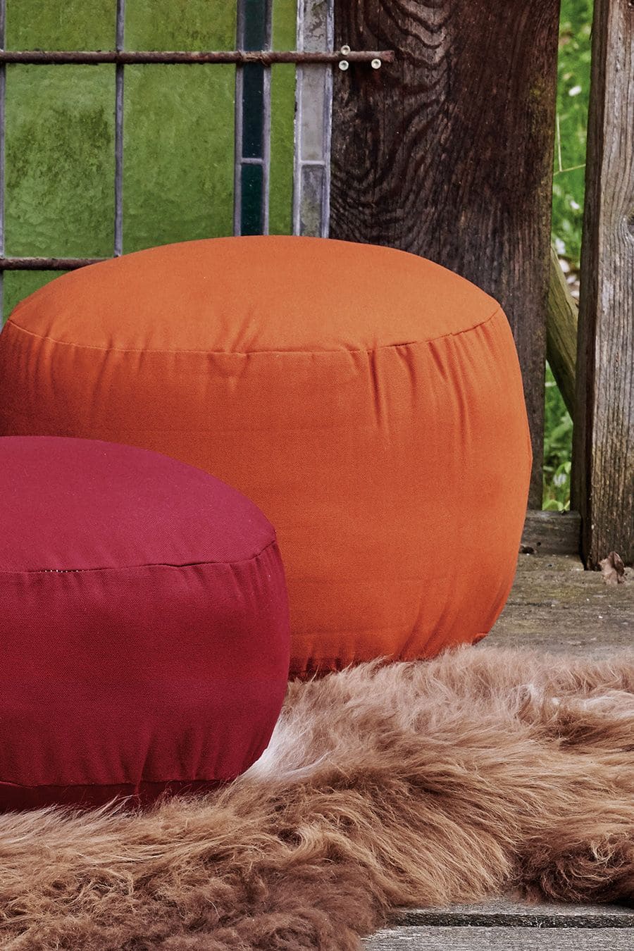 Rundes Sitzkissen groß oranges und rotes Sitzkissen in 2 Größen vom Finkhof aus Naturkautschuk, Wolle und bio Baumwolle (kbA) auf braunem Fell