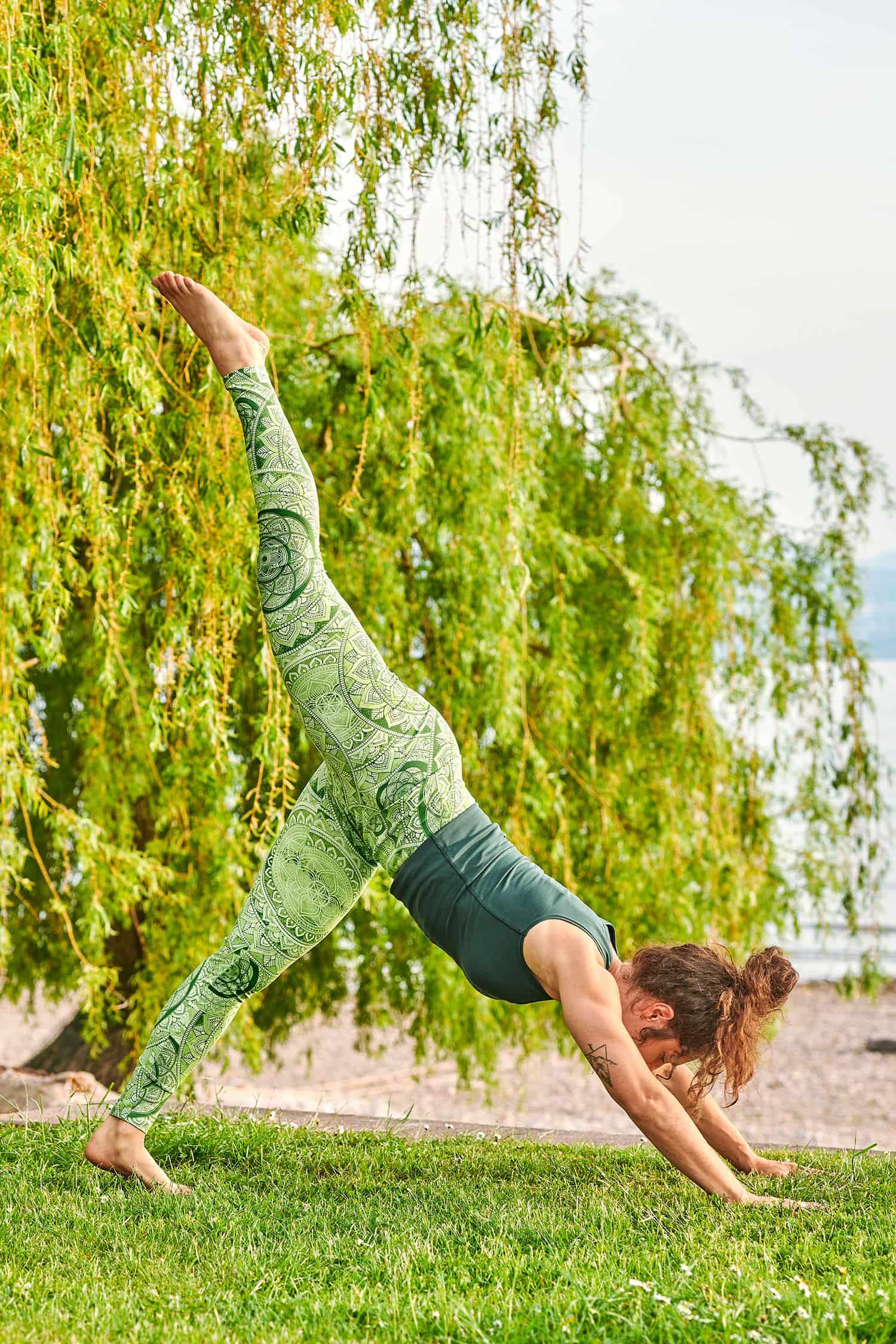 Frau in Yogapose trägt eine grün gemusterte Yoga Leggings aus bio Baumwolle (kbA) und Elasthan mit grünem Top
