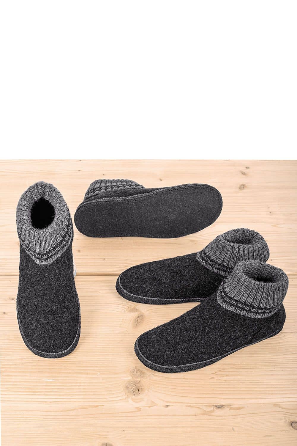 Hüttenschuhe mit Korkfußbett zwei Paar Hüttenschuhe mit Korkfußbett in anthrazit stehen auf hellem Holzuntergrund
