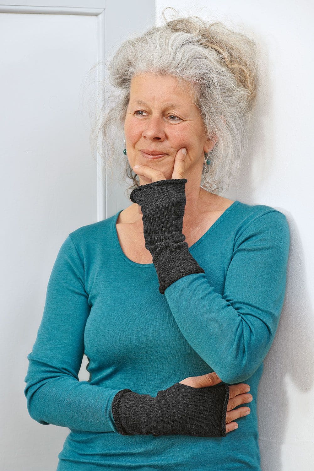 Frau trägt türkises Shirt und dunkelgraue Handstulpen aus bio Wolle (kbT) vom Finkhof