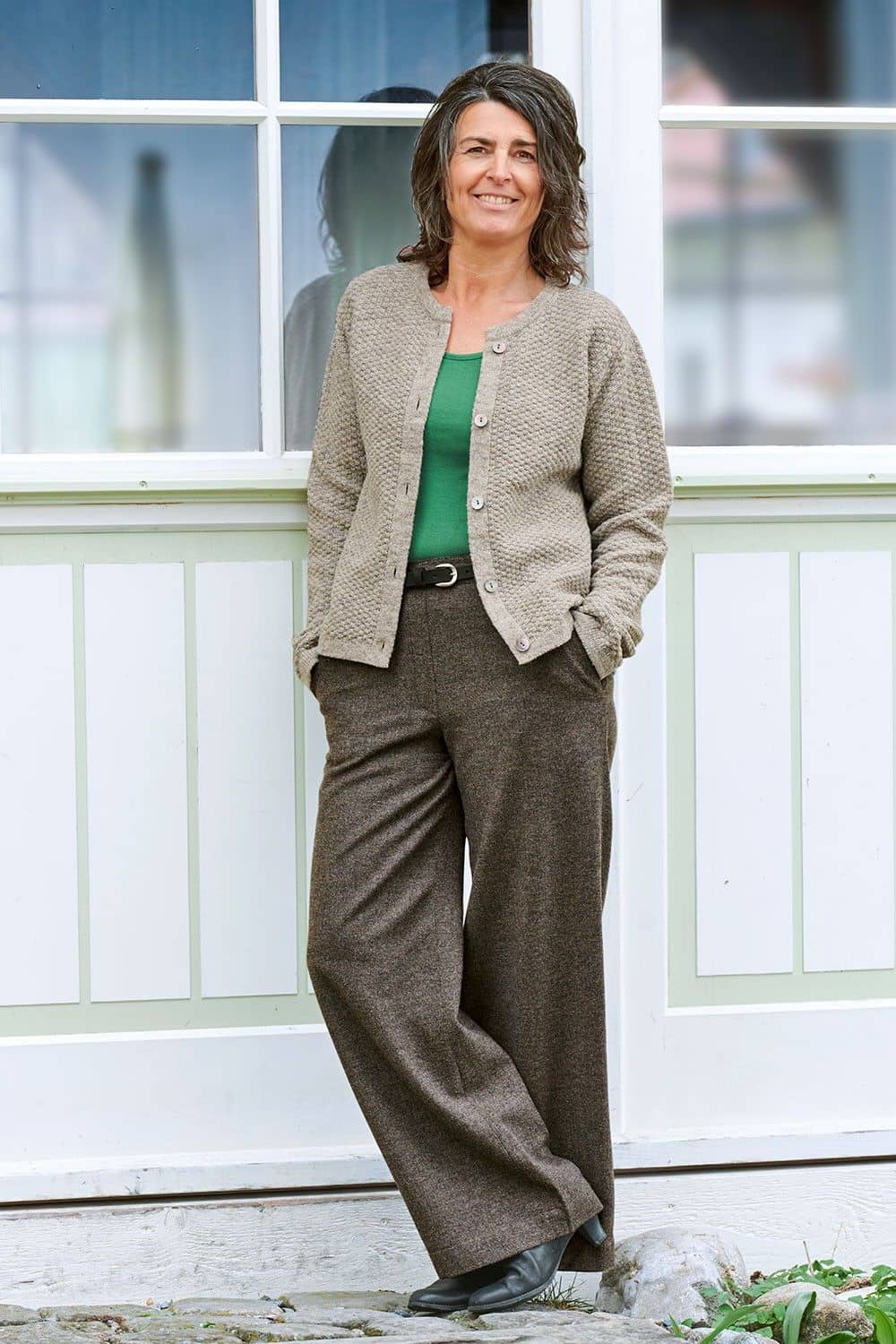 Frau trägt grünes Shirt, hellbraune Weste und eine braunmelierte weite Wollhose aus bio Wolle (kbT) vom Finkhof