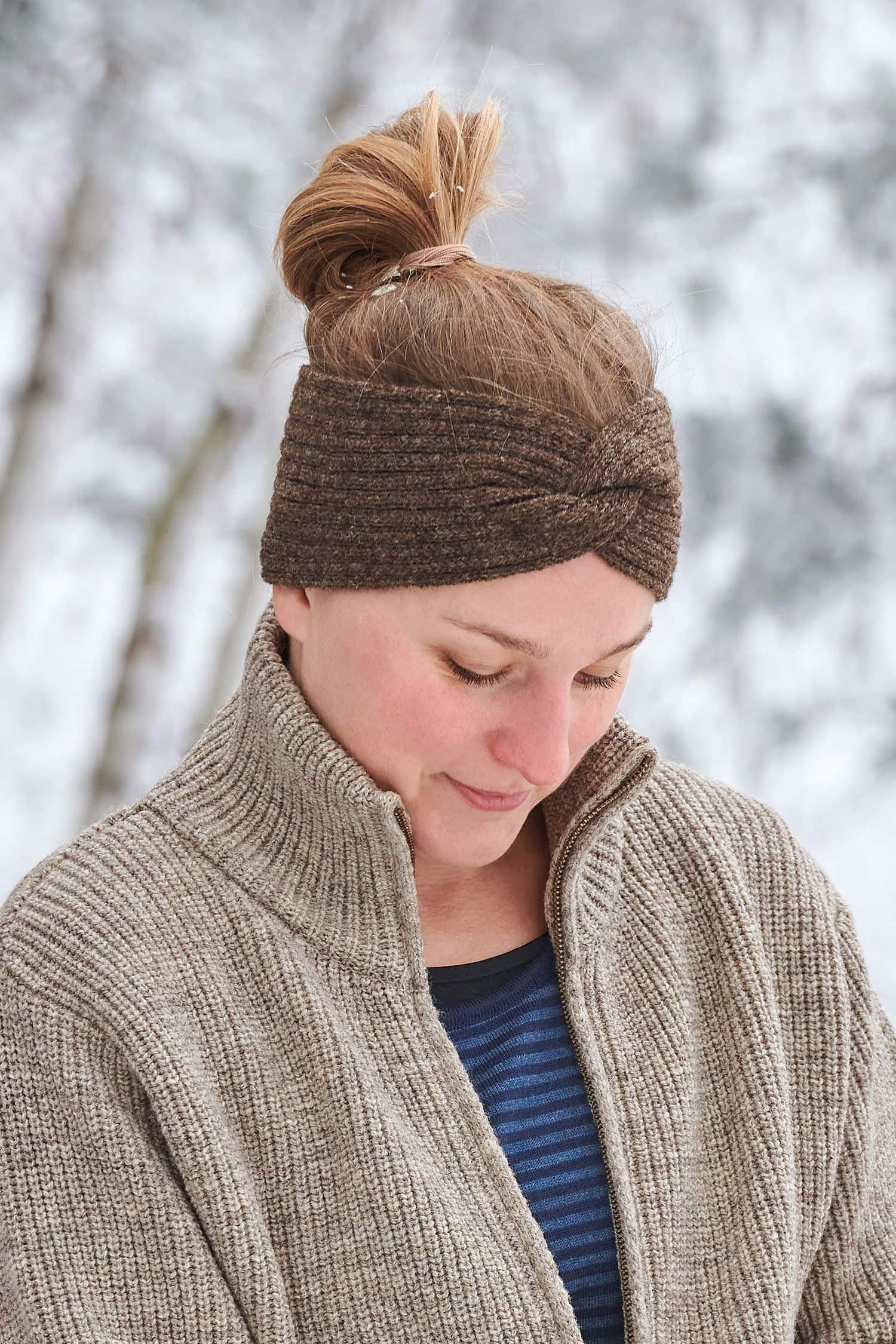 Frau trägt braunes Finkhof Stirnband mit Twist aus bio Wolle (kbT), einen Finkhof Troyer und ein blaues Streifenshirt