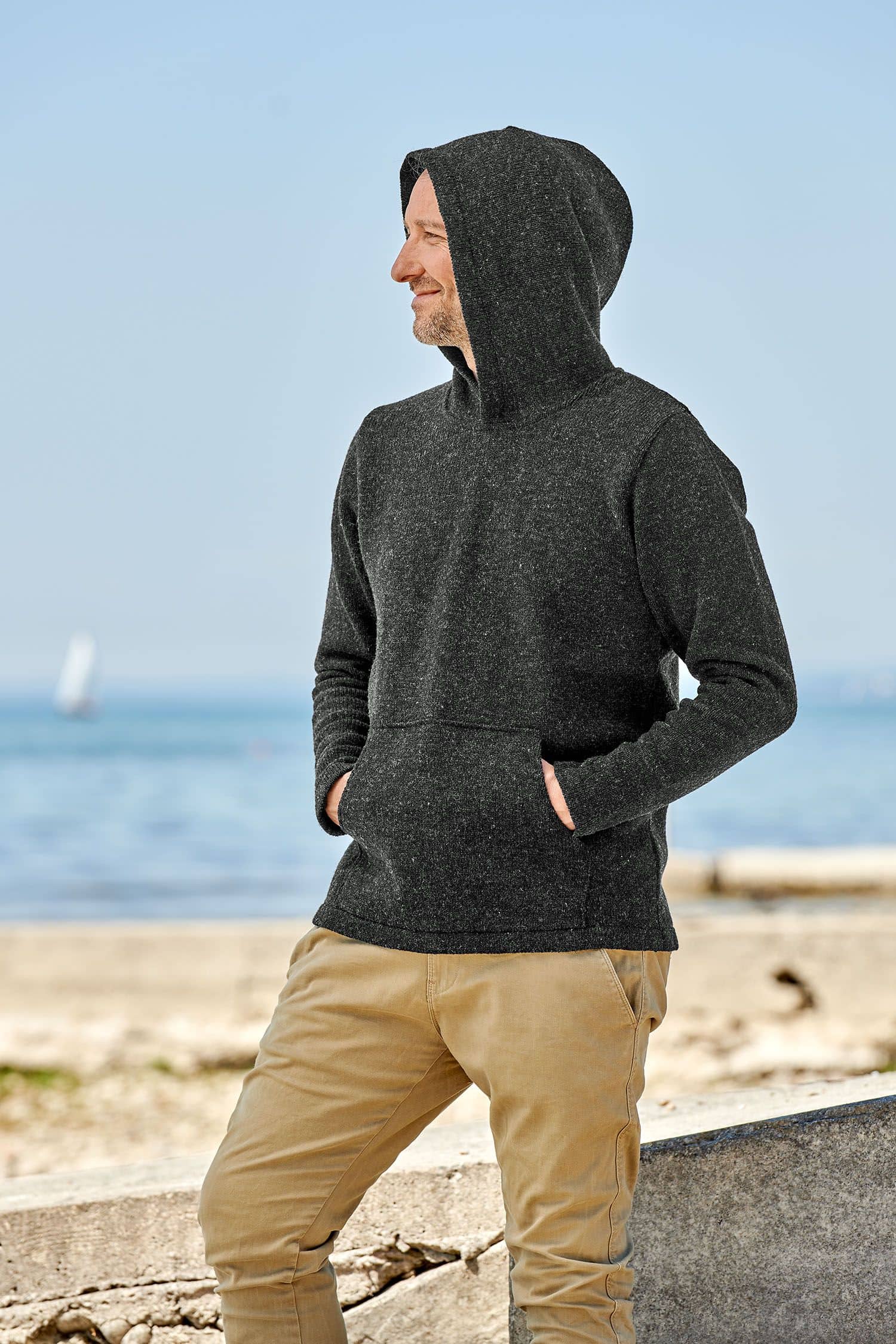 Mann trägt dunkelgrauen Pulli mit Kapuze vom Finkhof aus bio Merinowolle (kbT)