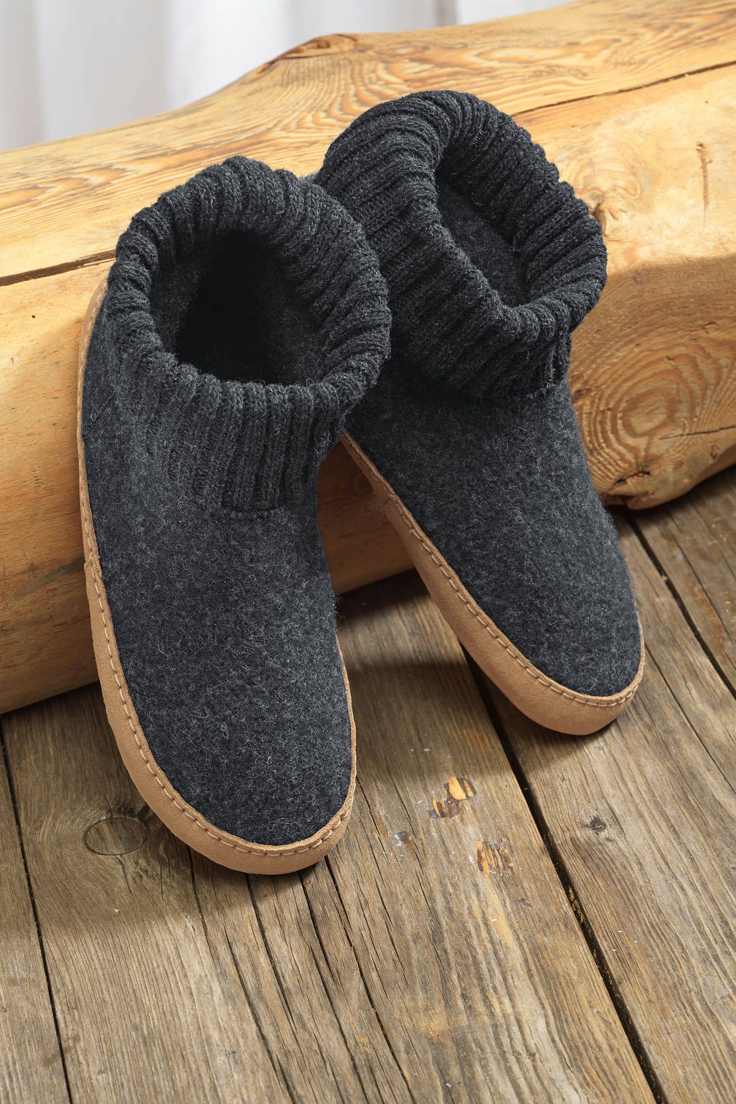 Paar dunkelgraue Finkhof Hüttenschuhe aus bio Wolle (kbT) und einer Sohle aus pflanzlich gegerbtem Rindsleder auf Baumstamm