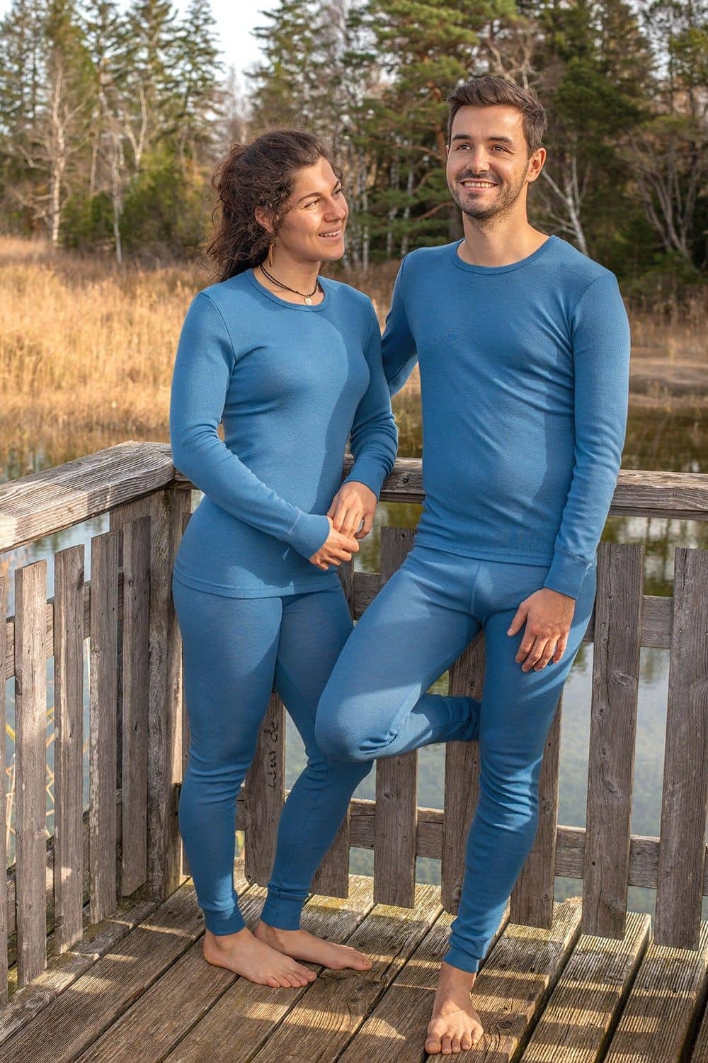Mann und Frau stehen auf Brücke und tragen blaue lange Unterhosen aus bio Wolle (kbT) mit blauen Shirts