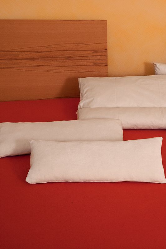 Lendenkissen 20 x 50 cm Finkhof Lendenkissen mit 20x50cm aus bio Wolle (kbT) und bio Baumwolle (kbA) auf braunem Bett mit rotem Laken