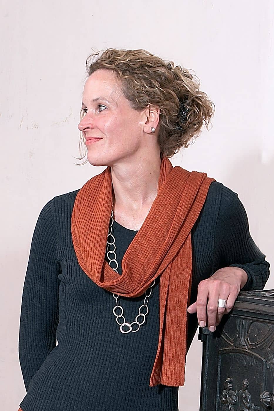 Frau mit grauem Shirt trägt orangen Strickschal aus bio Wolle (kbT) vom Finkhof