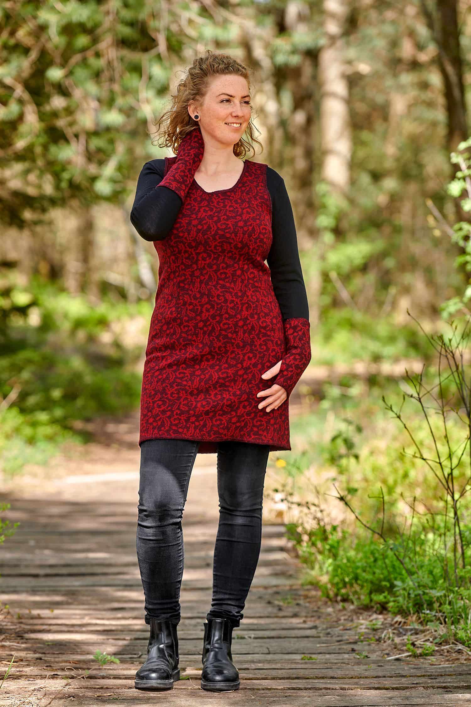 Frau mit schwarzer Jeans und Shirt und trägt eine rotes Strickkleid aus bio Wolle (kbT)