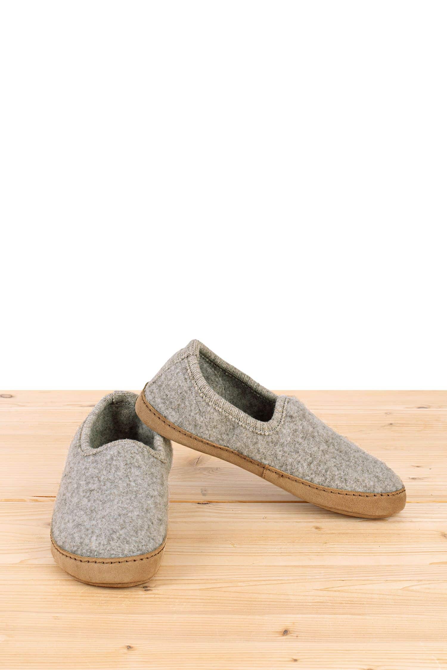 hellgraue Finkhof Hausschuhe aus bio Wolle (kbT) und pflanzlich gegerbtem Leder auf Holzboden von Vorne und Seite