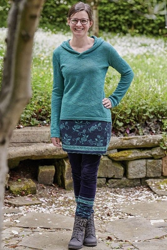 Beinstulpen Rose Frau trägt blaue Beinstulpen mit floralem Muster, passendem Cacheur, türkisem Pullover und Jeans