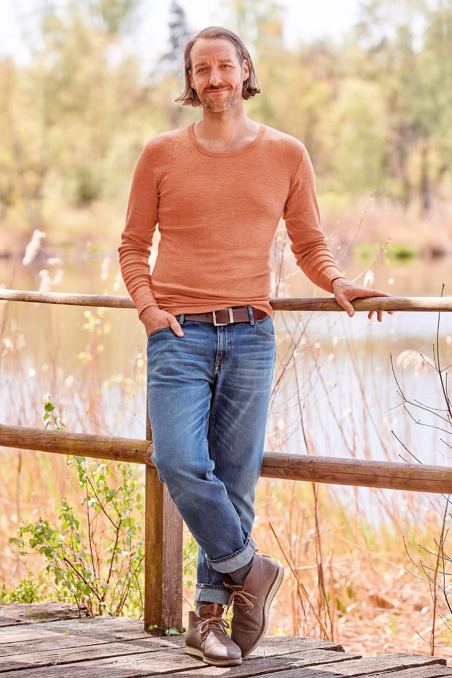 Mann mit Jeans trägt oranges Langarmshirt aus bio Wolle (kbT), bio Baumwolle (kbA) und Seide