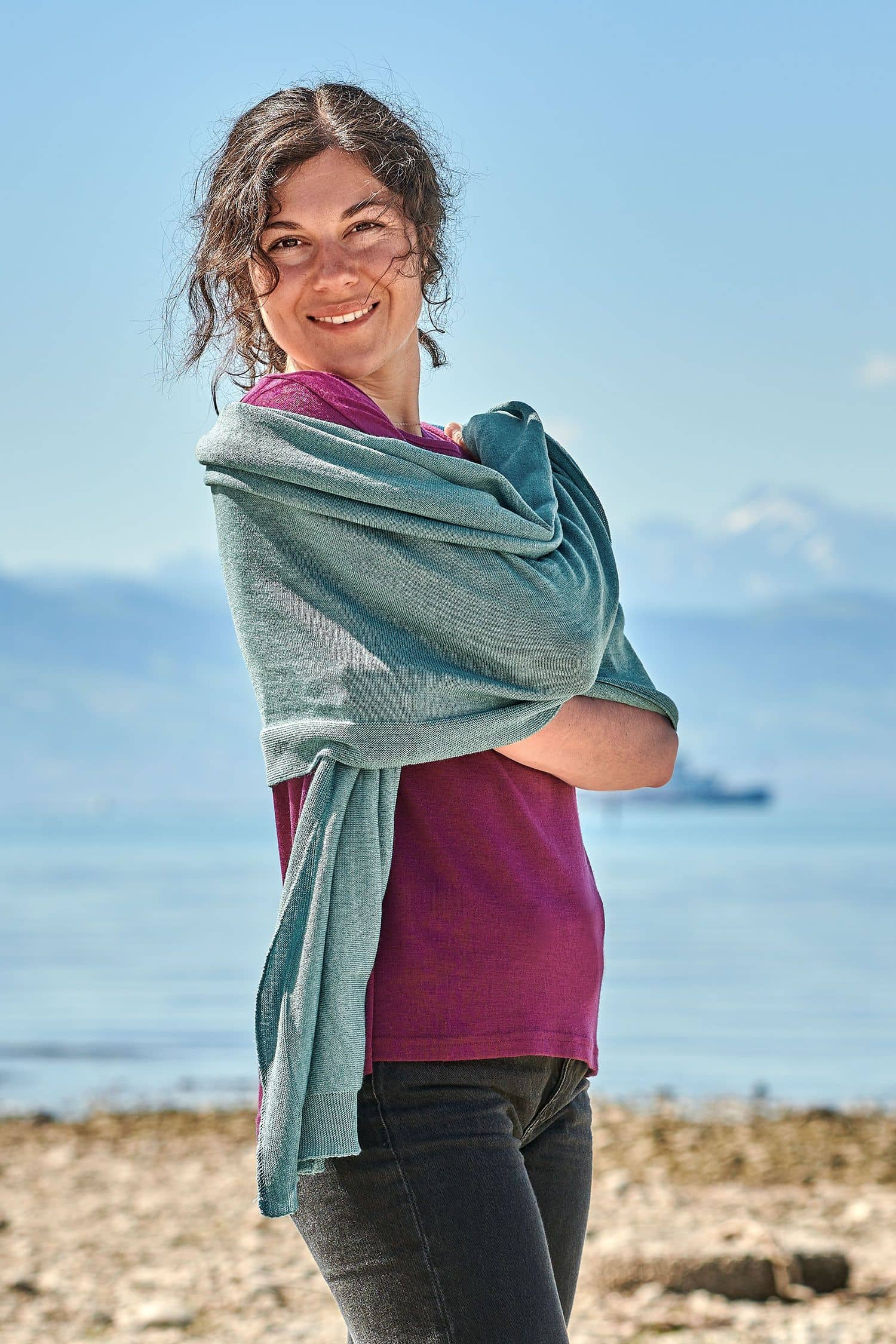 Feiner Merinoschal aqua Frau mit beerefarbenem Shirt trägt blauen Merinoschal aus bio Wolle (kbT) vom Finkhof über den Schultern