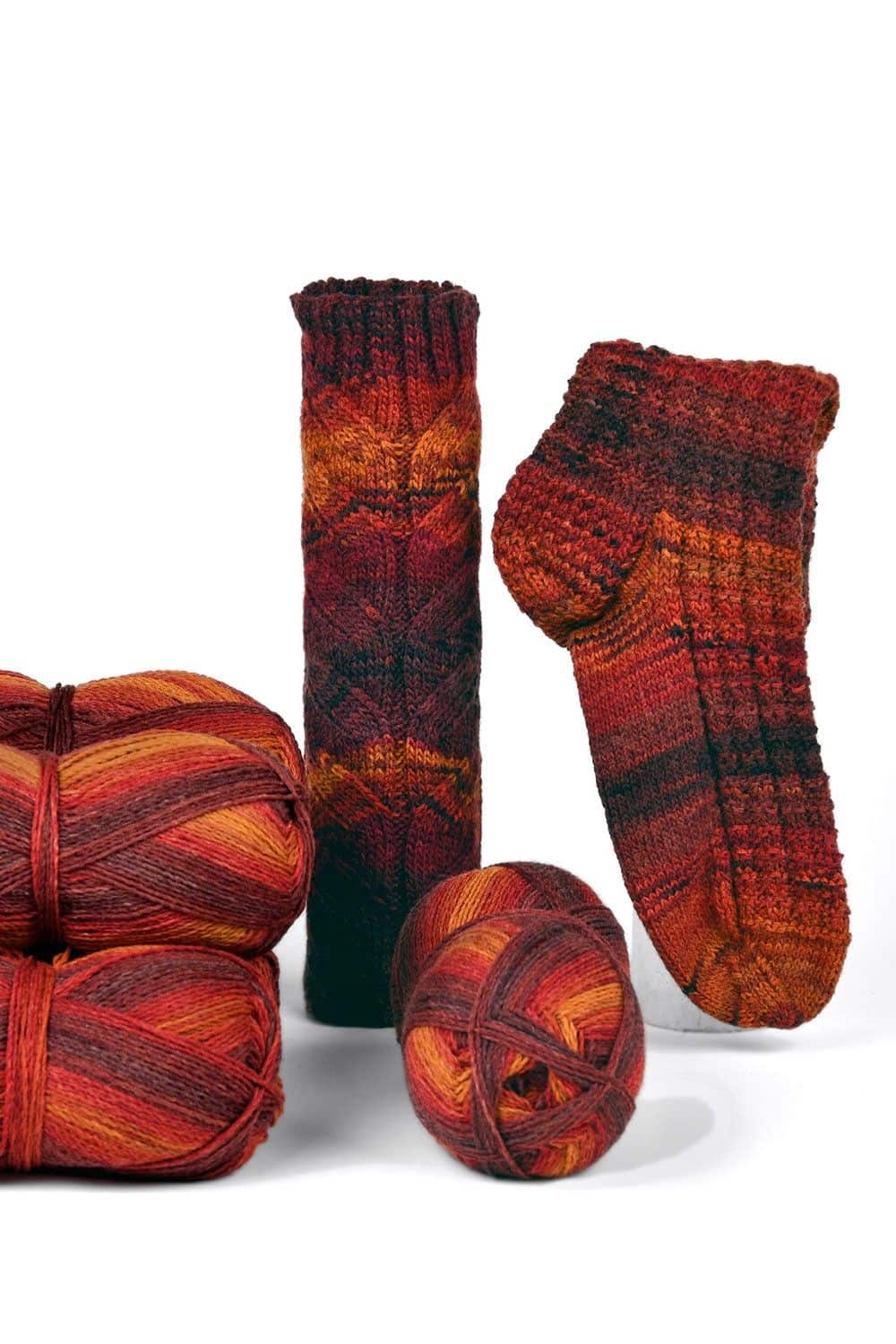 feine Finkhof Sockenwolle mit rot orangem Farbverlauf aus bio Wolle (kbT) mit Knäulen und fertiger Socke