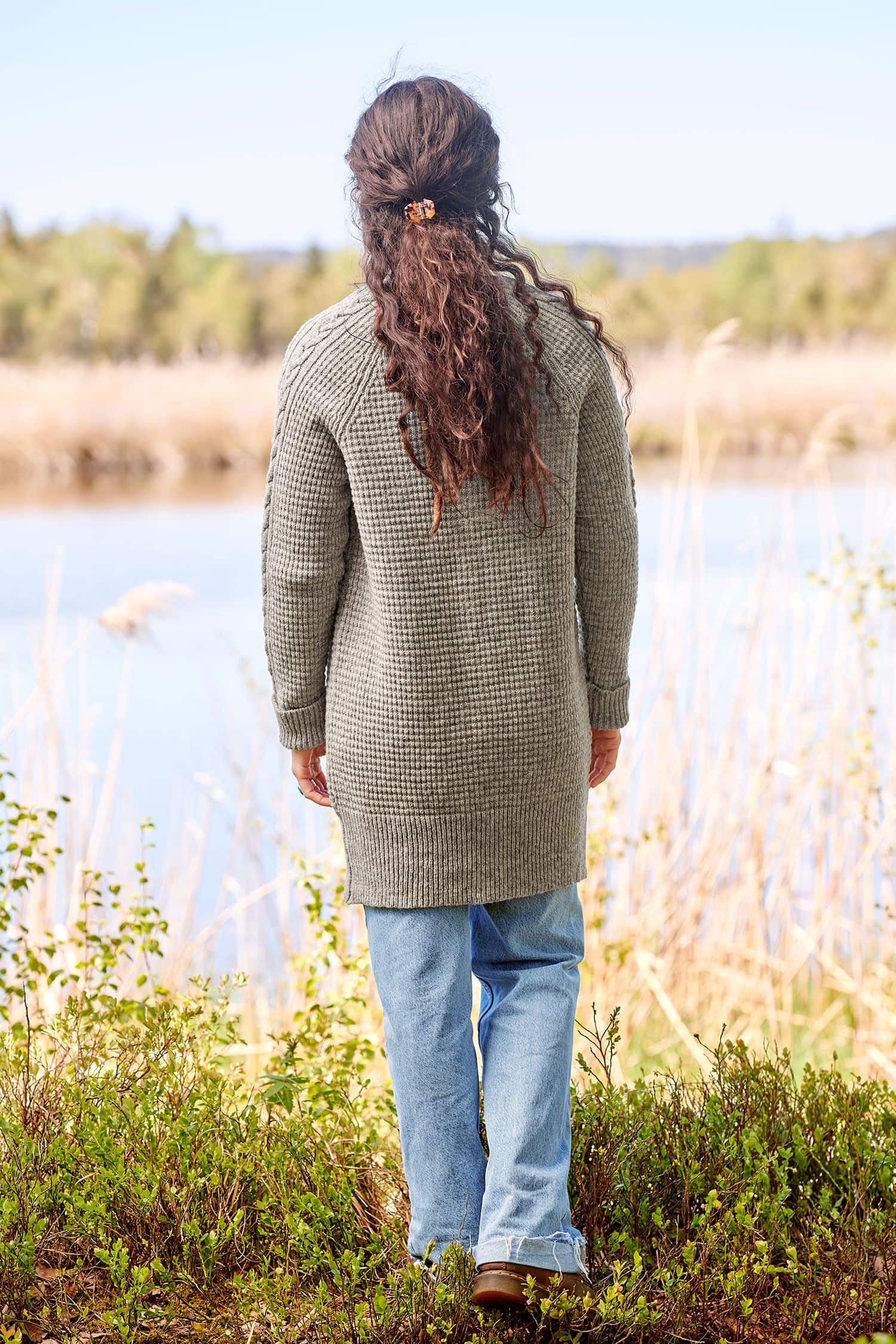 Rückansicht von Frau mit Jeans und grauem ungefärbtem Cardigan mit Zopfmuster aus bio Wolle (kbT) vom Finkhof