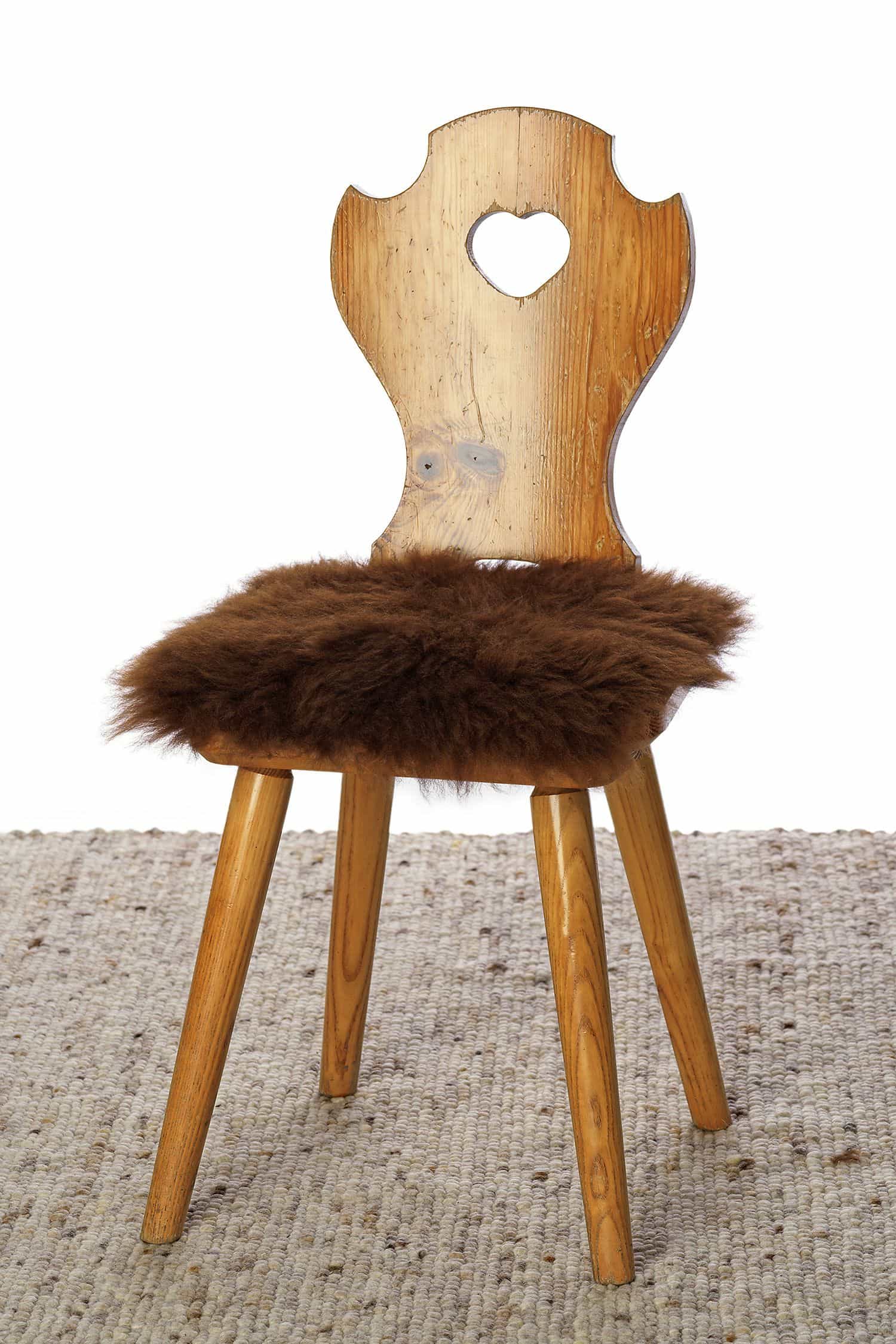 quadratische Stuhlauflage aus braunem pflanzlich gefärbtem Schaffell vom Finkhof auf braunem Stuhl