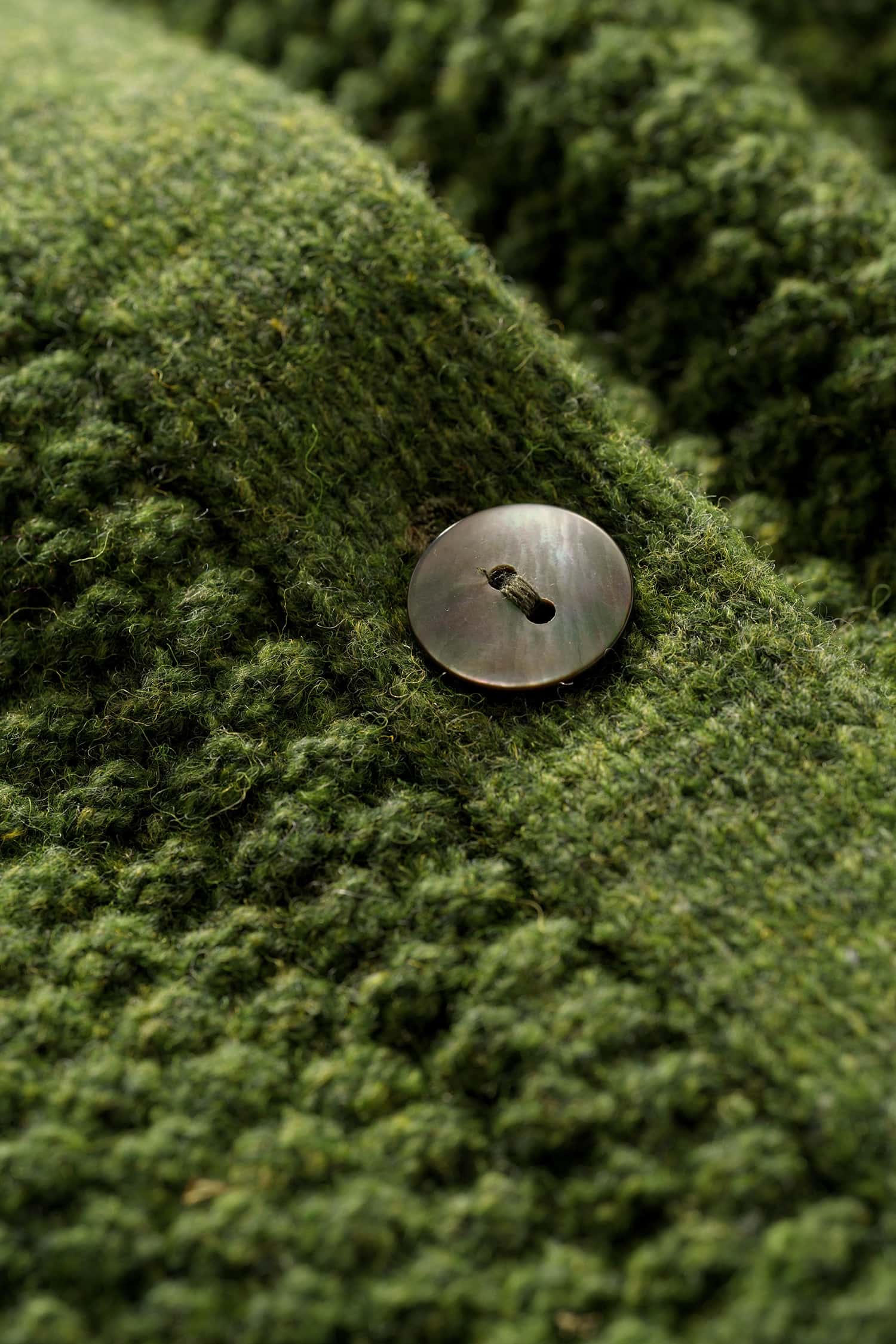 Nahaufnahme eines Perlmuttknopfes der grünen Strukturjacke vom Finkhof aus Bio-Schurwolle