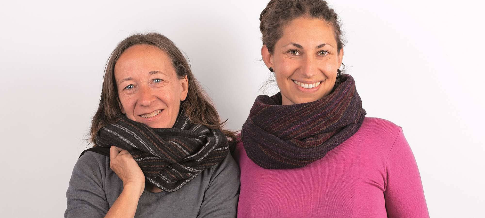 Frauen mit unifarbenen Shirts tragen dunkle Loopschals mit Streifenkreppoptik