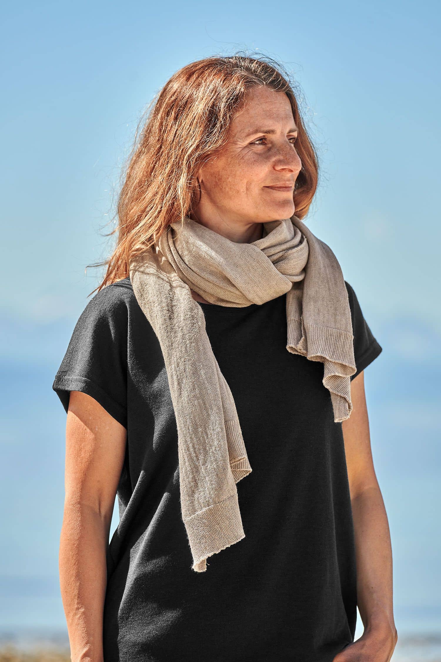 Frau mit schwarzem Shirt trägt einen beigen feinen Merinoschal aus bio Wolle (kbT) vom Finkhof