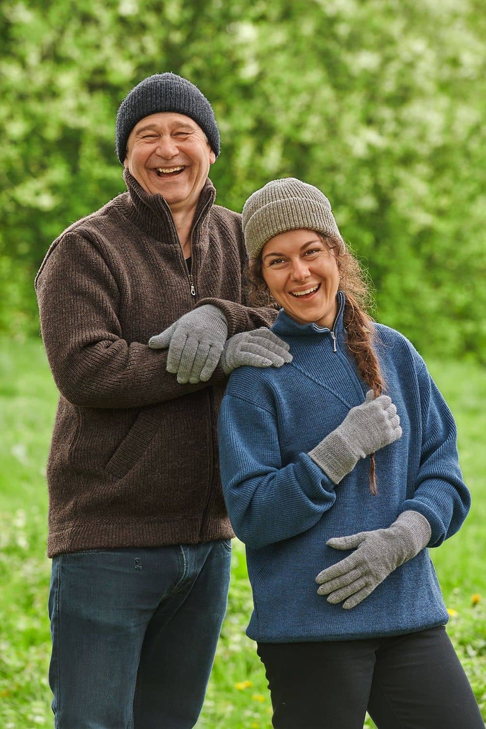 Mann und Frau mit Finkhof Troyer und Mütze tragen graue Strickhandschuhe mit Fingern aus bio Wolle (kbT) vom Finkhof