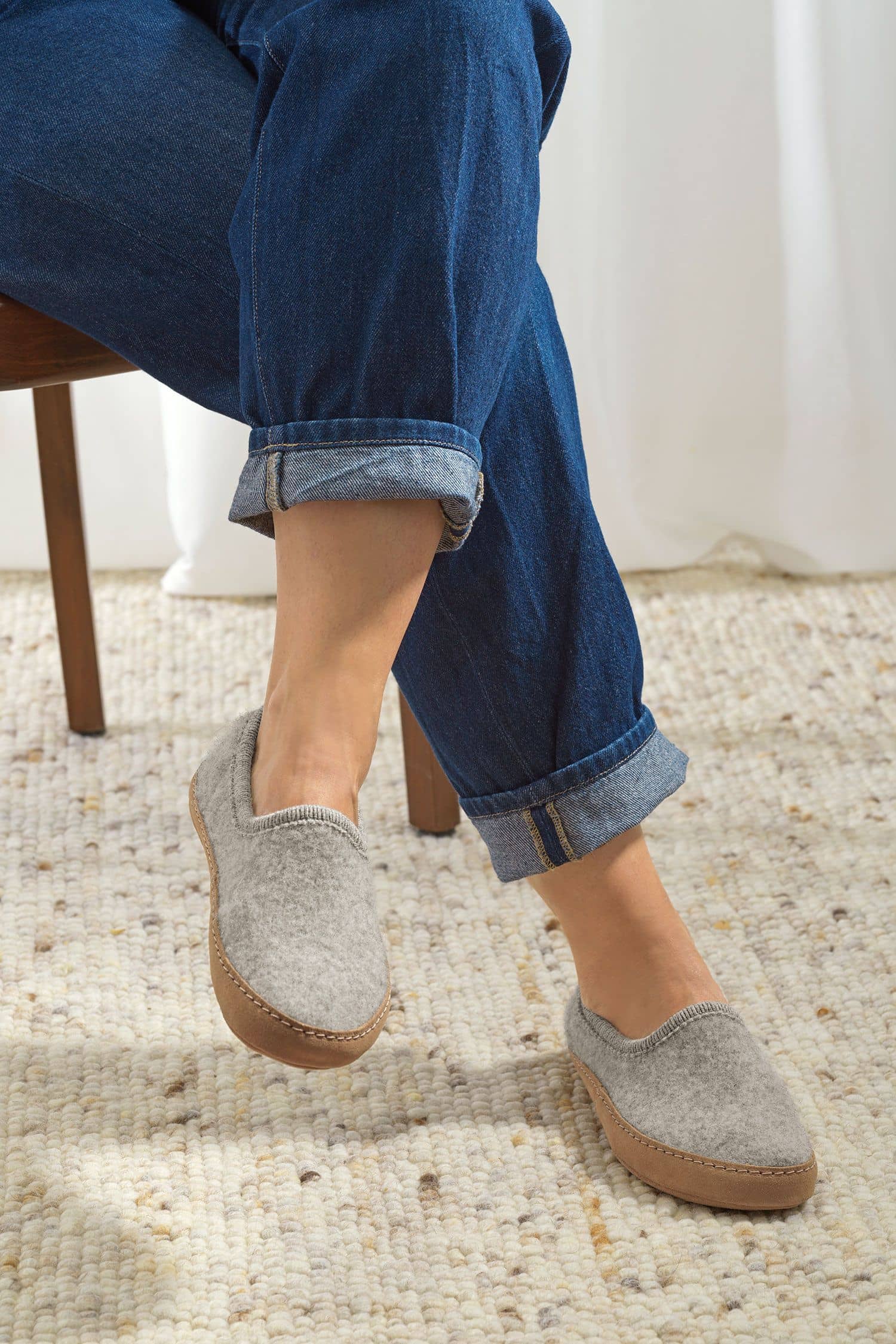 Person trägt hellgraue Finkhof Hausschuhe aus bio Wolle (kbT) mit einer Sohle aus pflanzlich gegerbtem Rindsleder