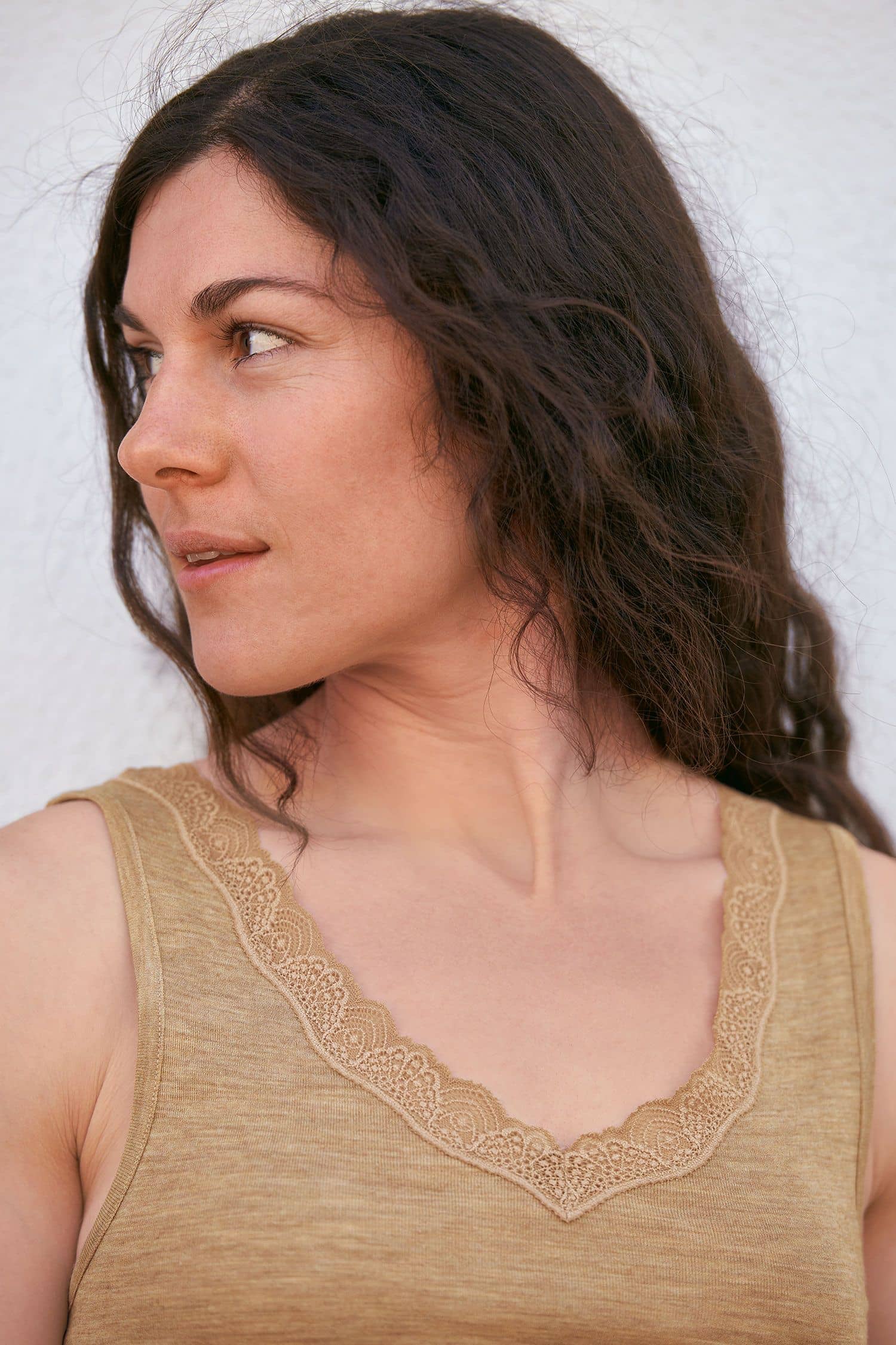Portraitaufnahme von Frau mit beigem Achselhemd aus bio Wolle (kbT) und Seide mit spitzenbesetzem V Ausschnitt