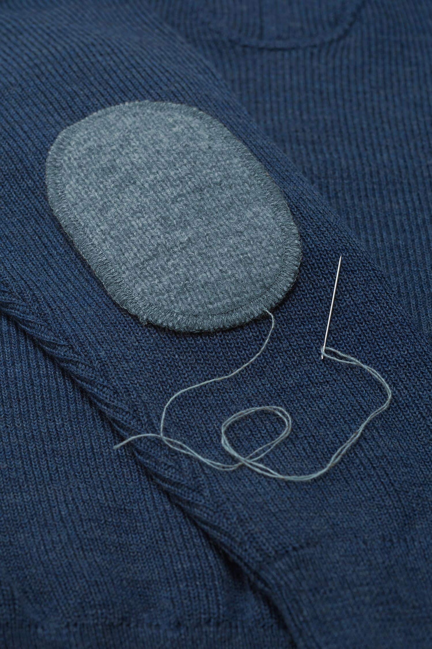 rauchblauer Ellenbogenpatch aus bio Wolle (kbT) vom Finkhof wird auf blauen Pulli genäht