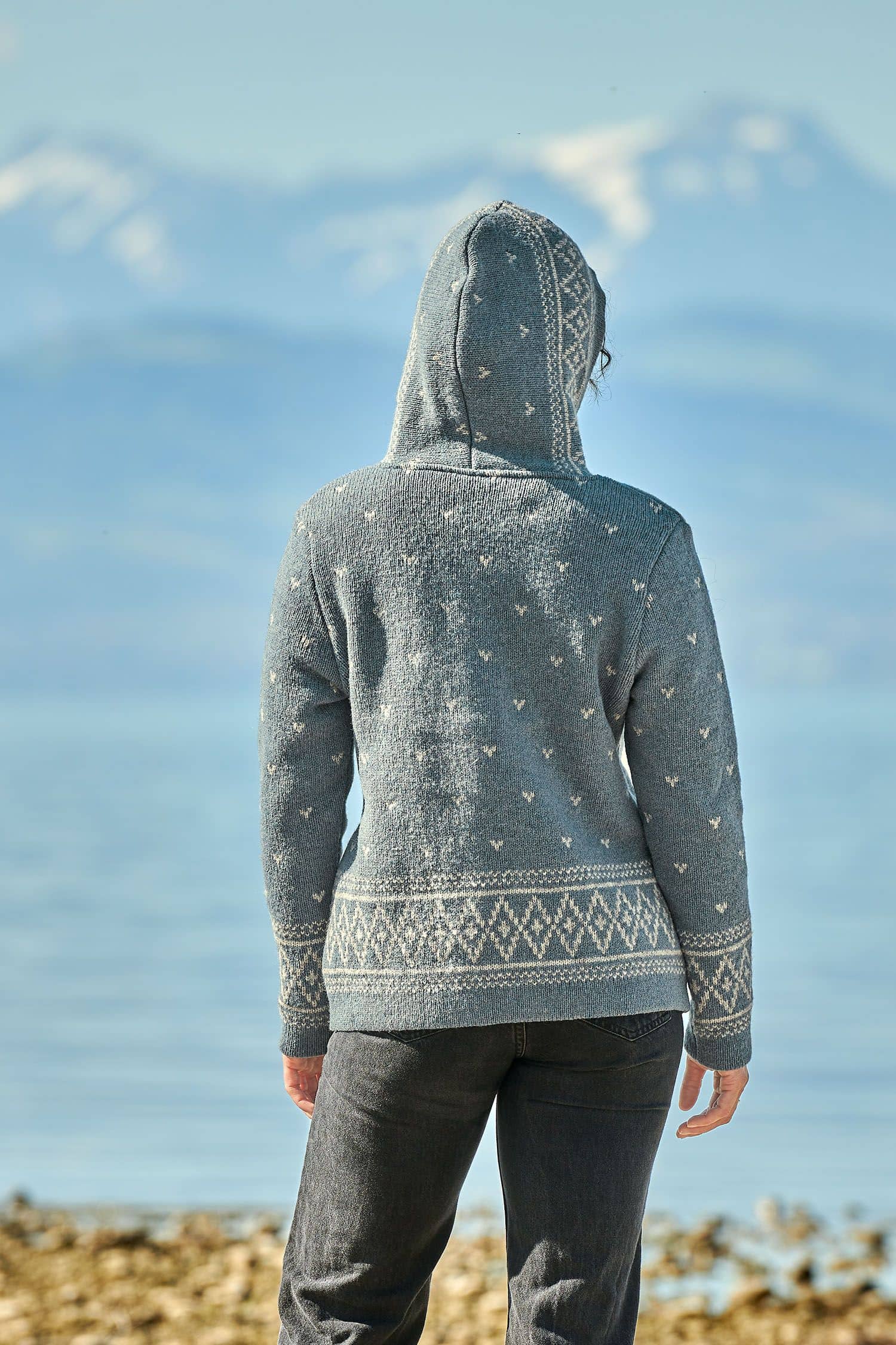 Rückansicht von Frau die Kapuze der rauchblauen Norwegerjacke aus bio Wolle (kbT) vom Finkhof trägt