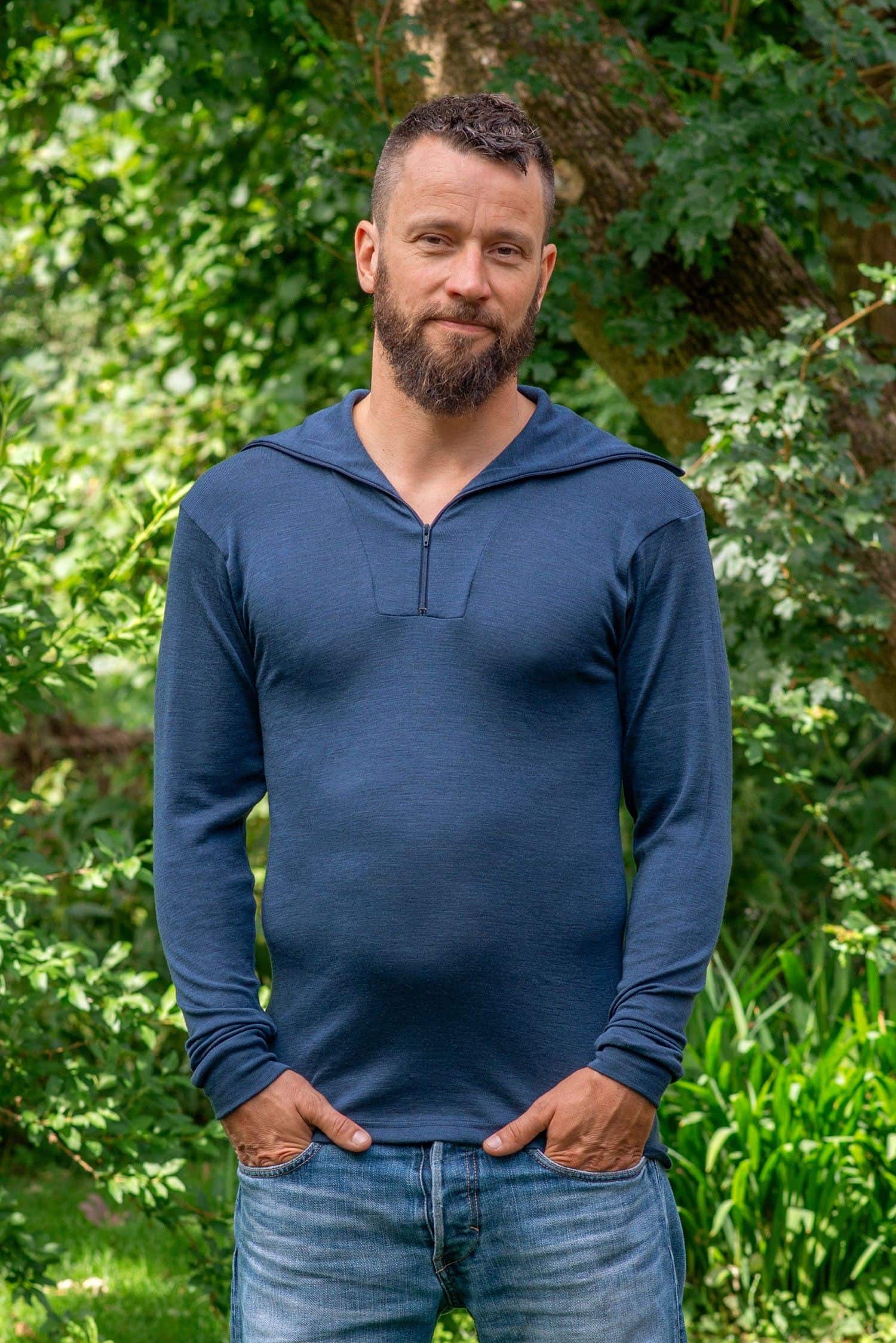Mann steht im Garten und trägt Jeans und marineblauen Sportrolli aus bio Wolle (kbT) und Seide mit Reißverschluss